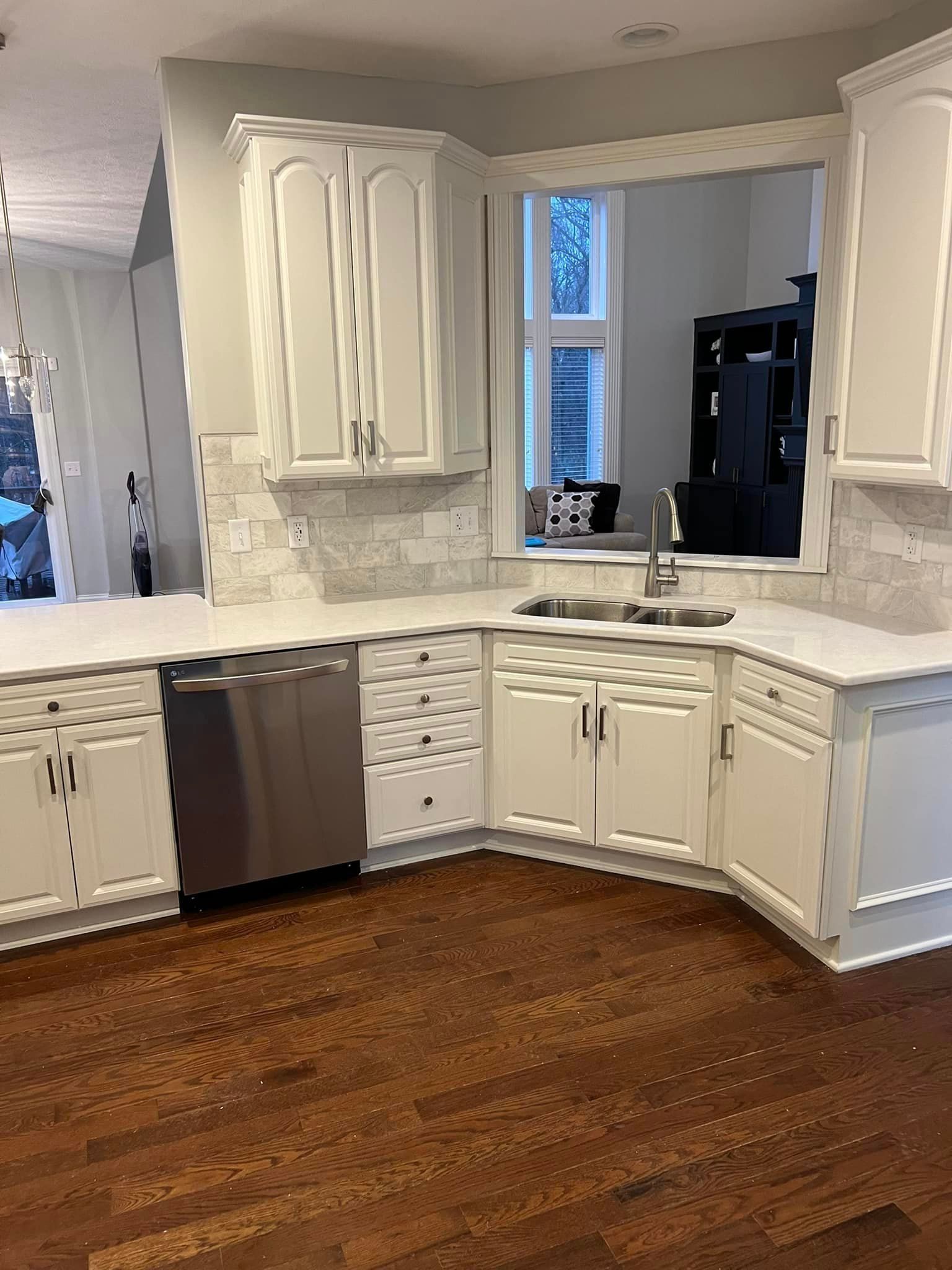 A kitchen with white cabinets , stainless steel appliances , and hardwood floors.