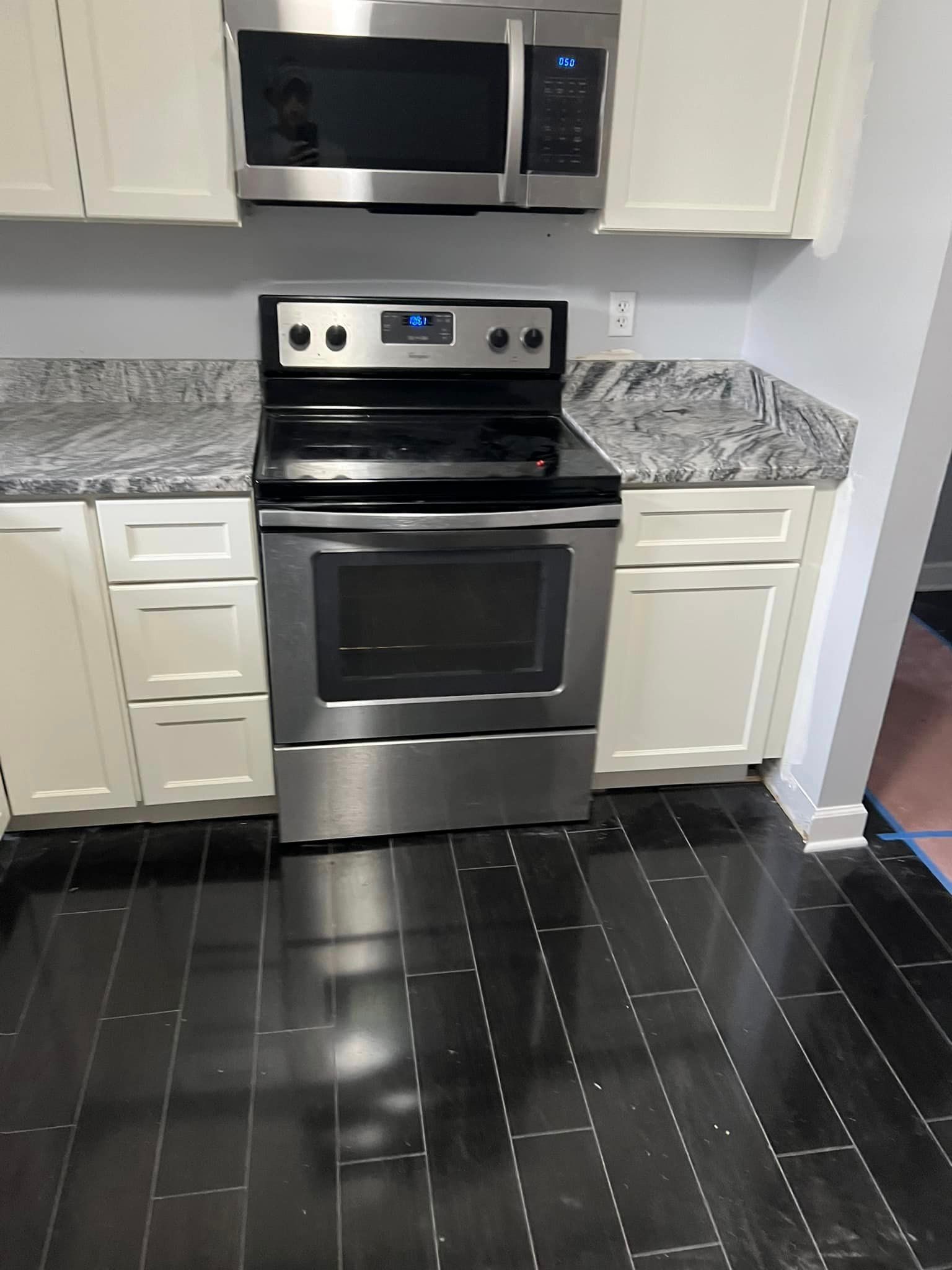 A kitchen with a stove , microwave , and cabinets.