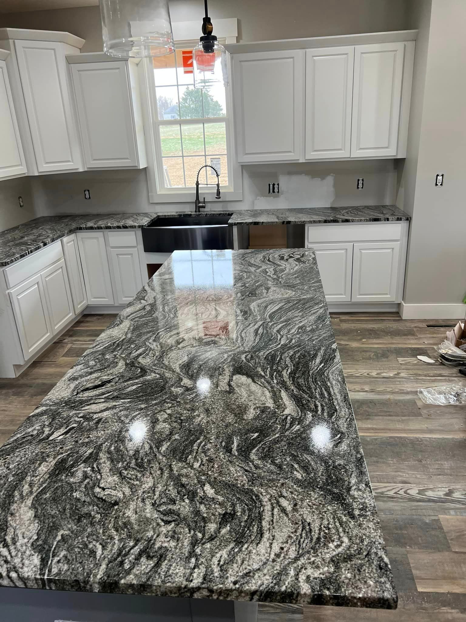 A kitchen with granite counter tops and white cabinets.
