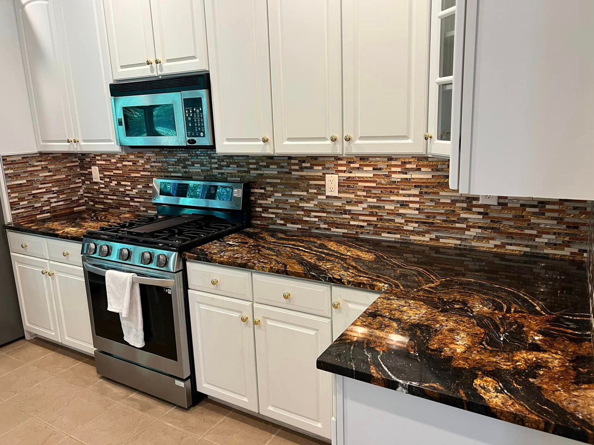 A kitchen with a stove , microwave , sink and cabinets.