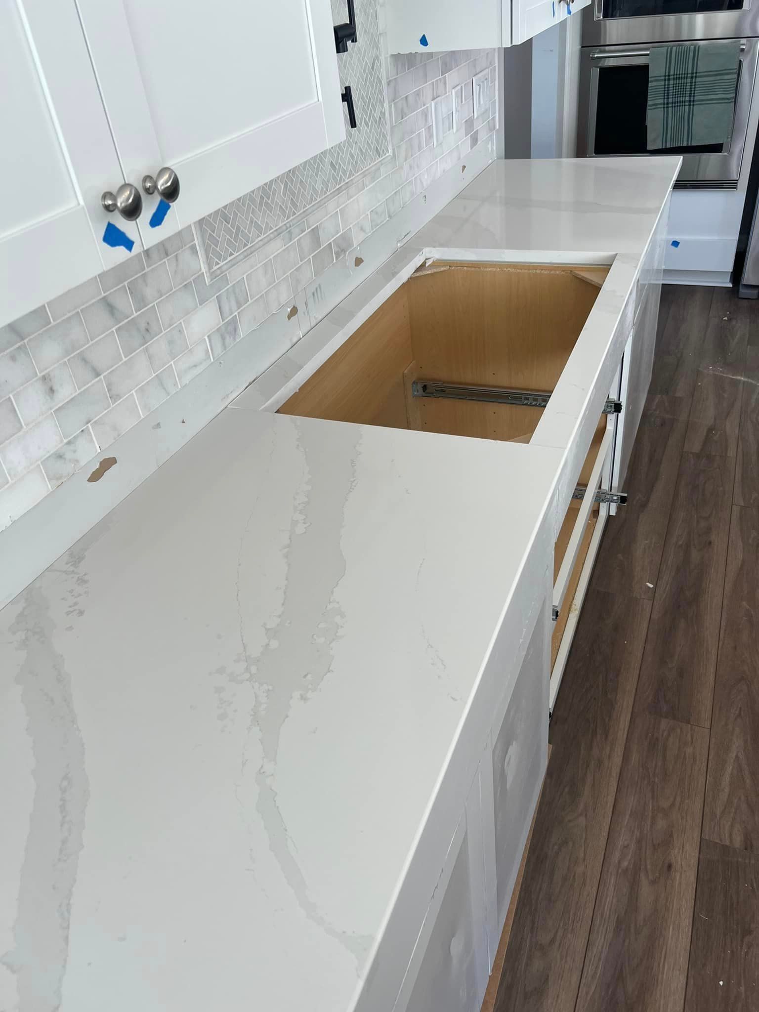 A kitchen with white cabinets and a large sink.