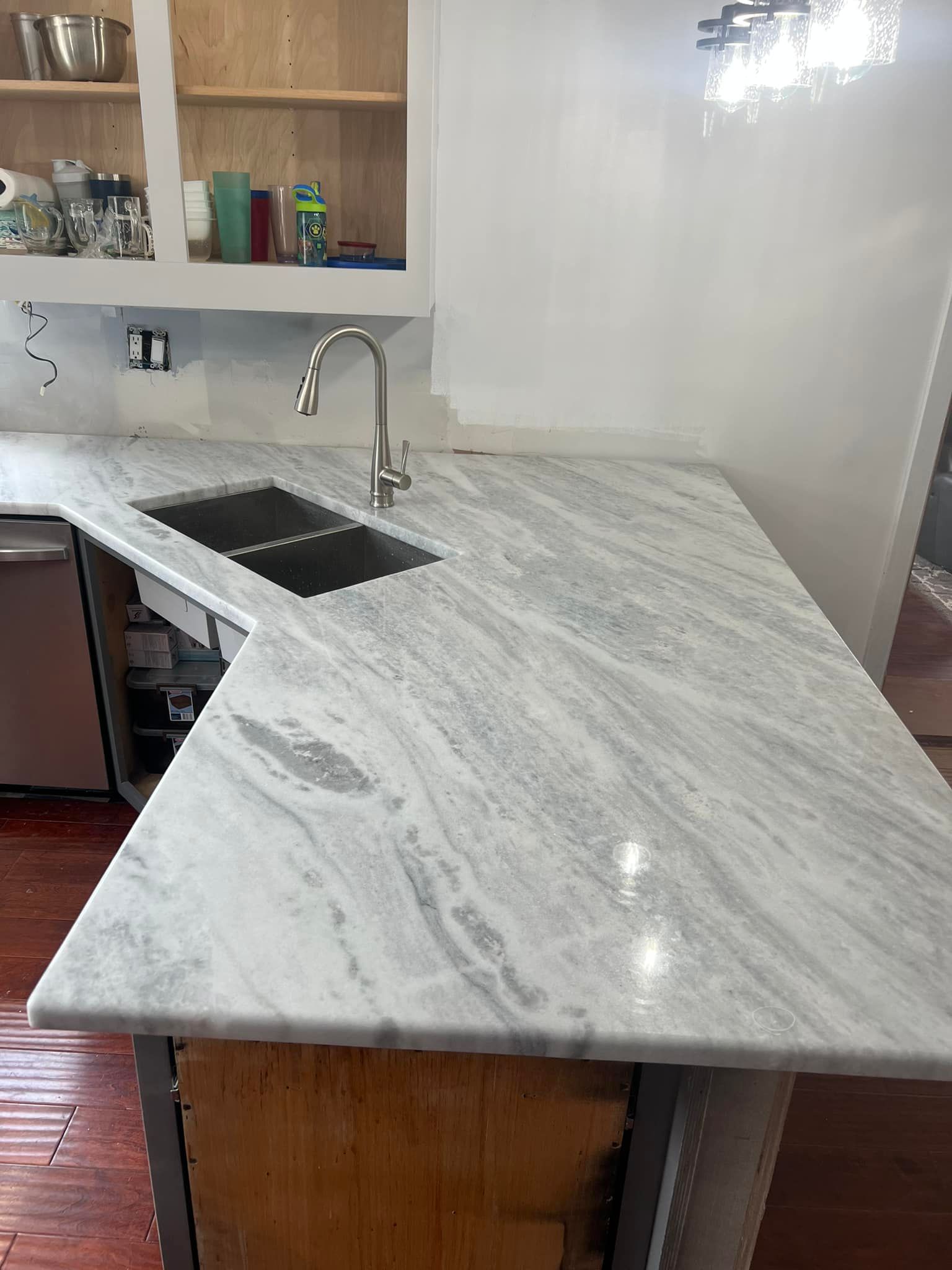 A kitchen with a marble counter top and a sink.