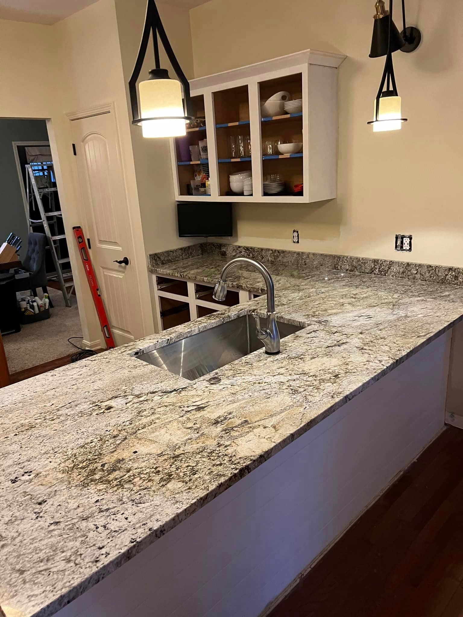 A kitchen with granite counter tops and a stainless steel sink.