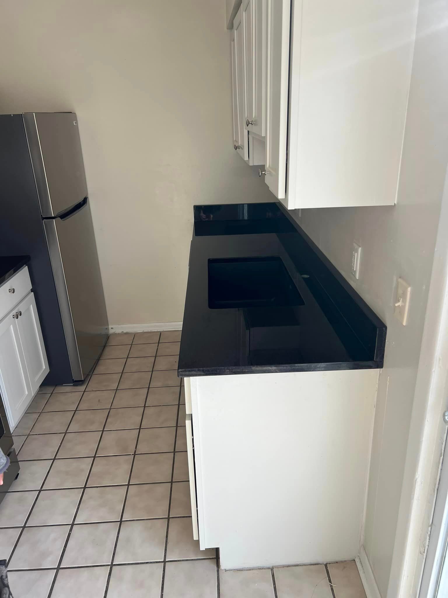 A kitchen with black counter tops and white cabinets
