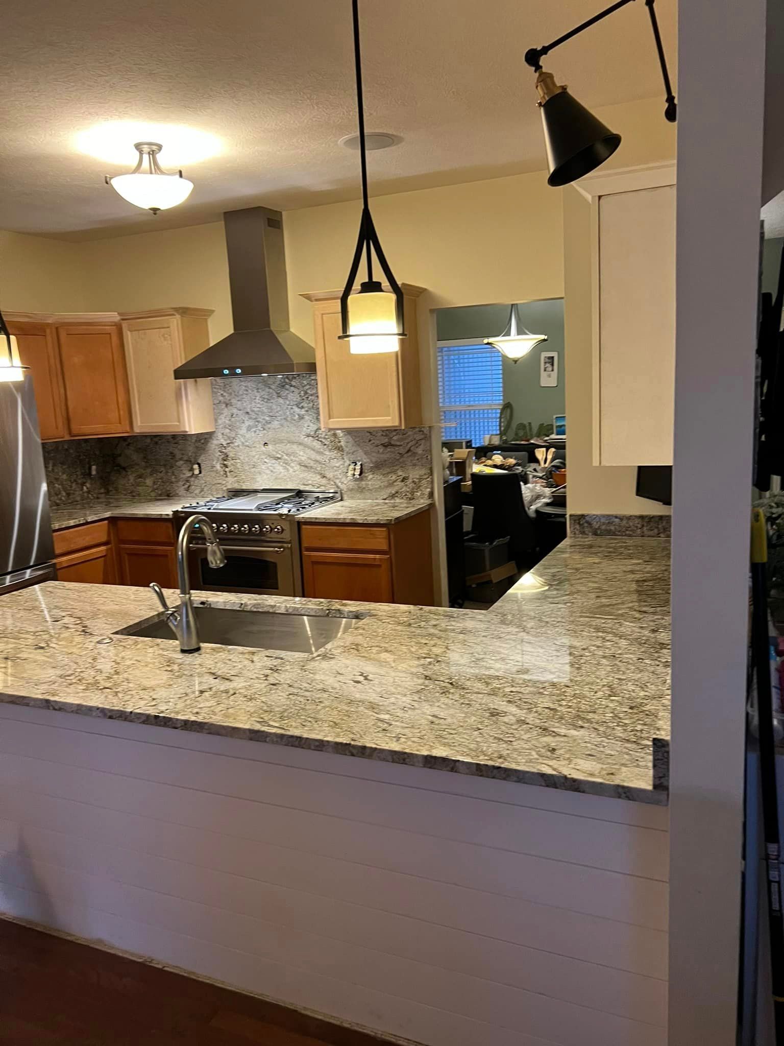 A kitchen with granite counter tops , stainless steel appliances , and wooden cabinets.