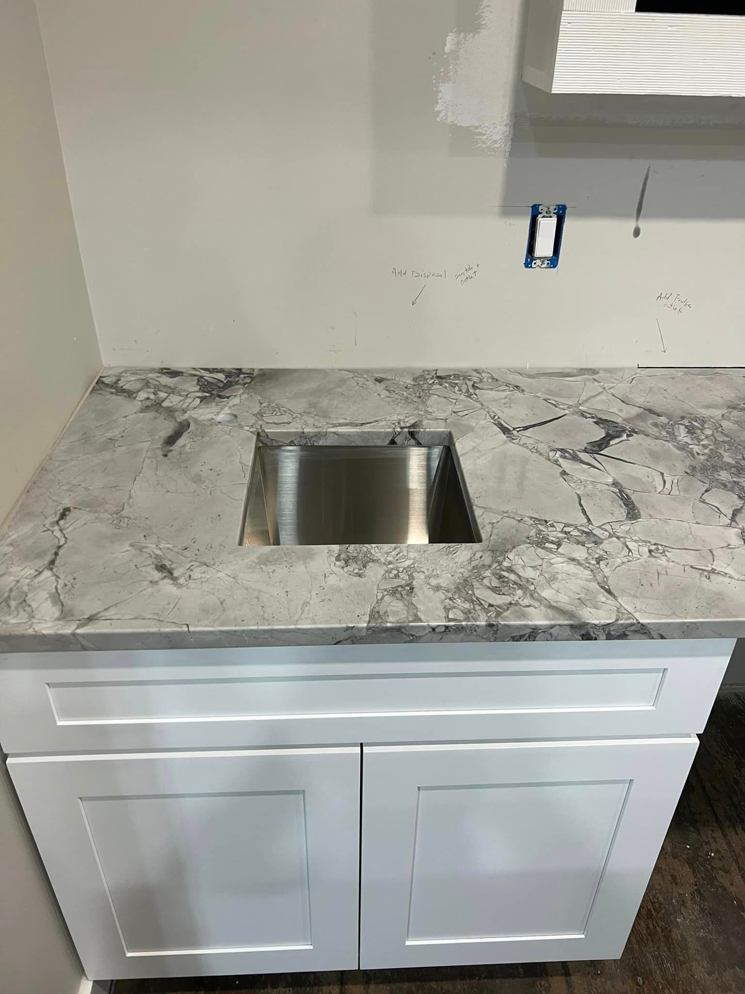 A kitchen counter with a stainless steel sink and granite counter top.