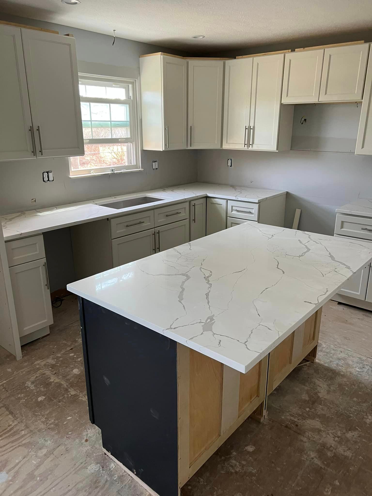 A kitchen with white cabinets and a large island in the middle.