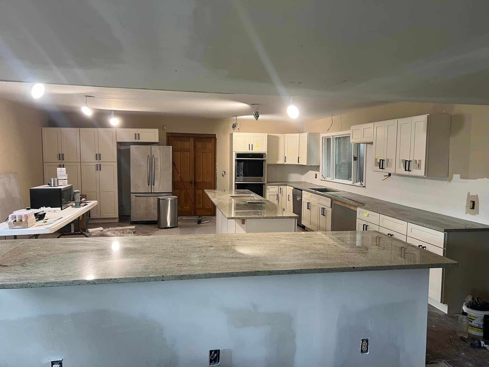 A kitchen under construction with granite counter tops and stainless steel appliances.