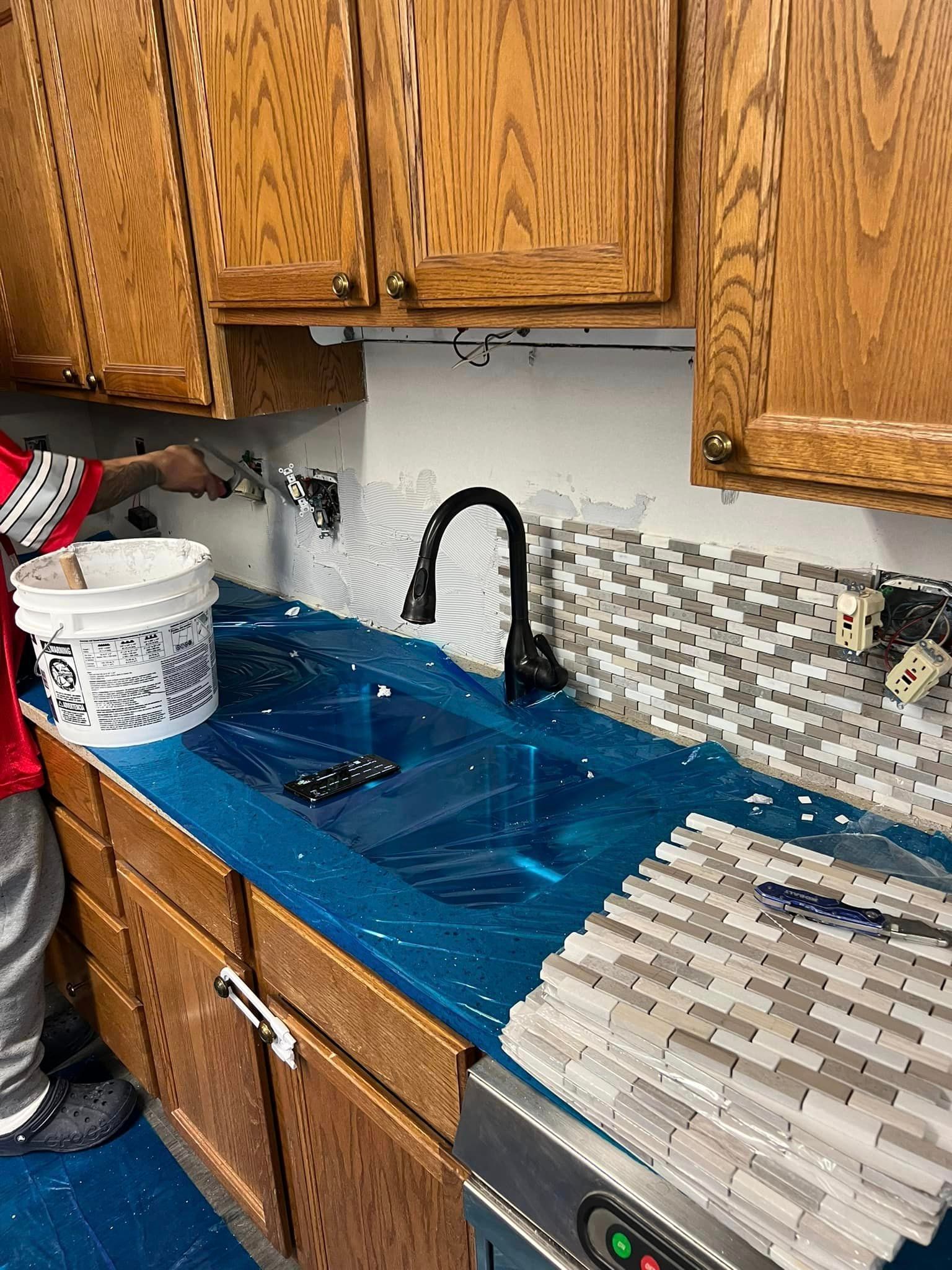 A man is standing next to a sink in a kitchen.
