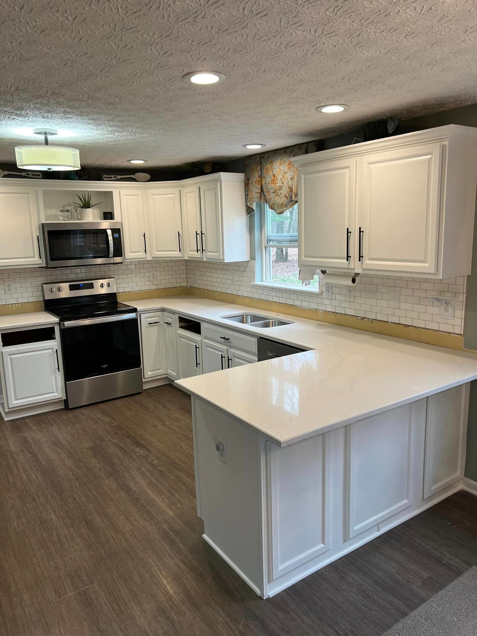 A kitchen with white cabinets , stainless steel appliances , and a large island.