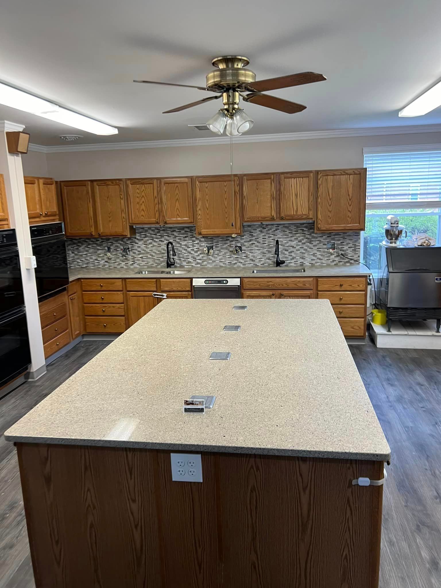 A kitchen with a large island and a ceiling fan.