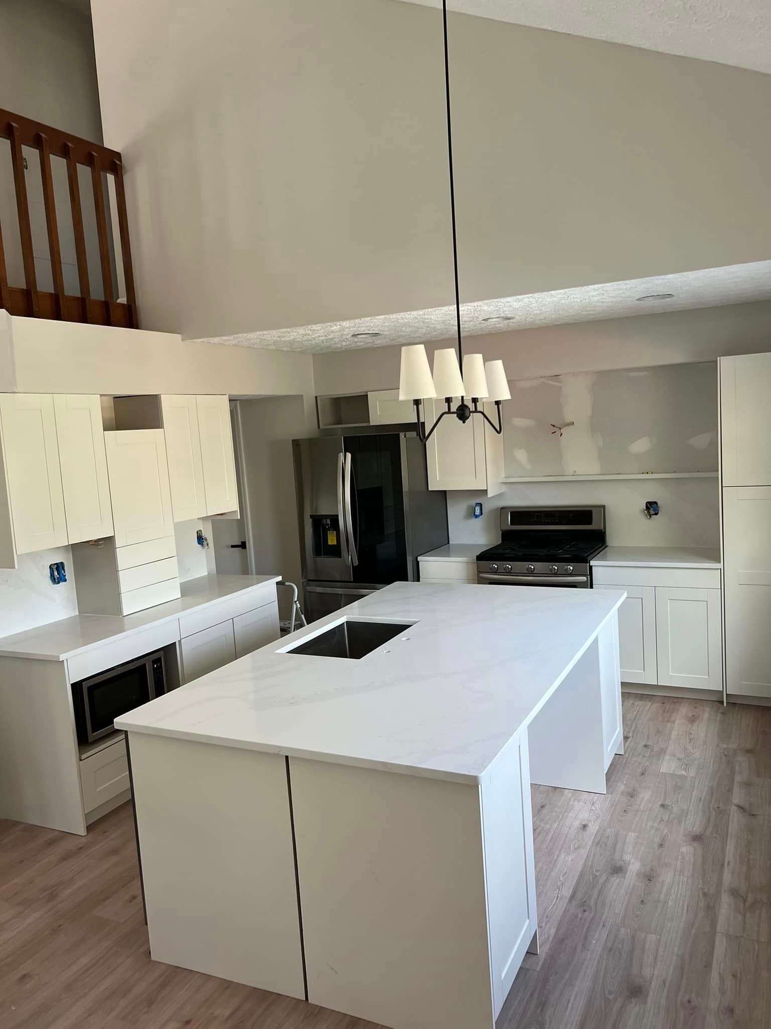 A kitchen with a large island in the middle and a chandelier hanging from the ceiling.