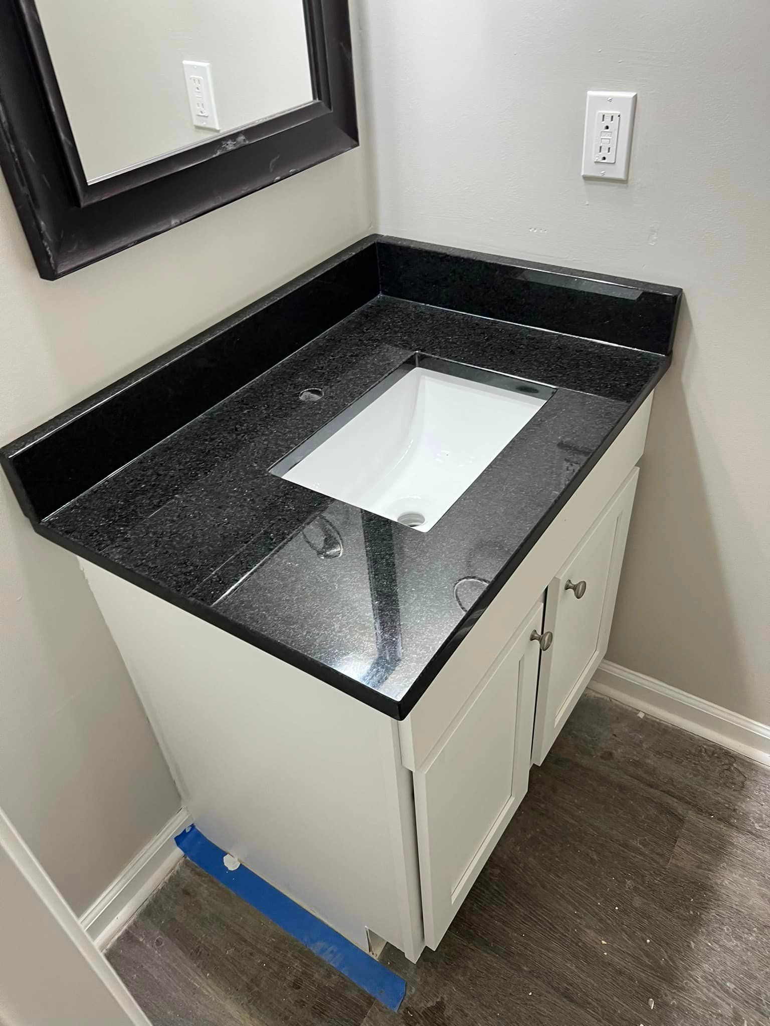 A bathroom vanity with a black granite counter top and a sink.