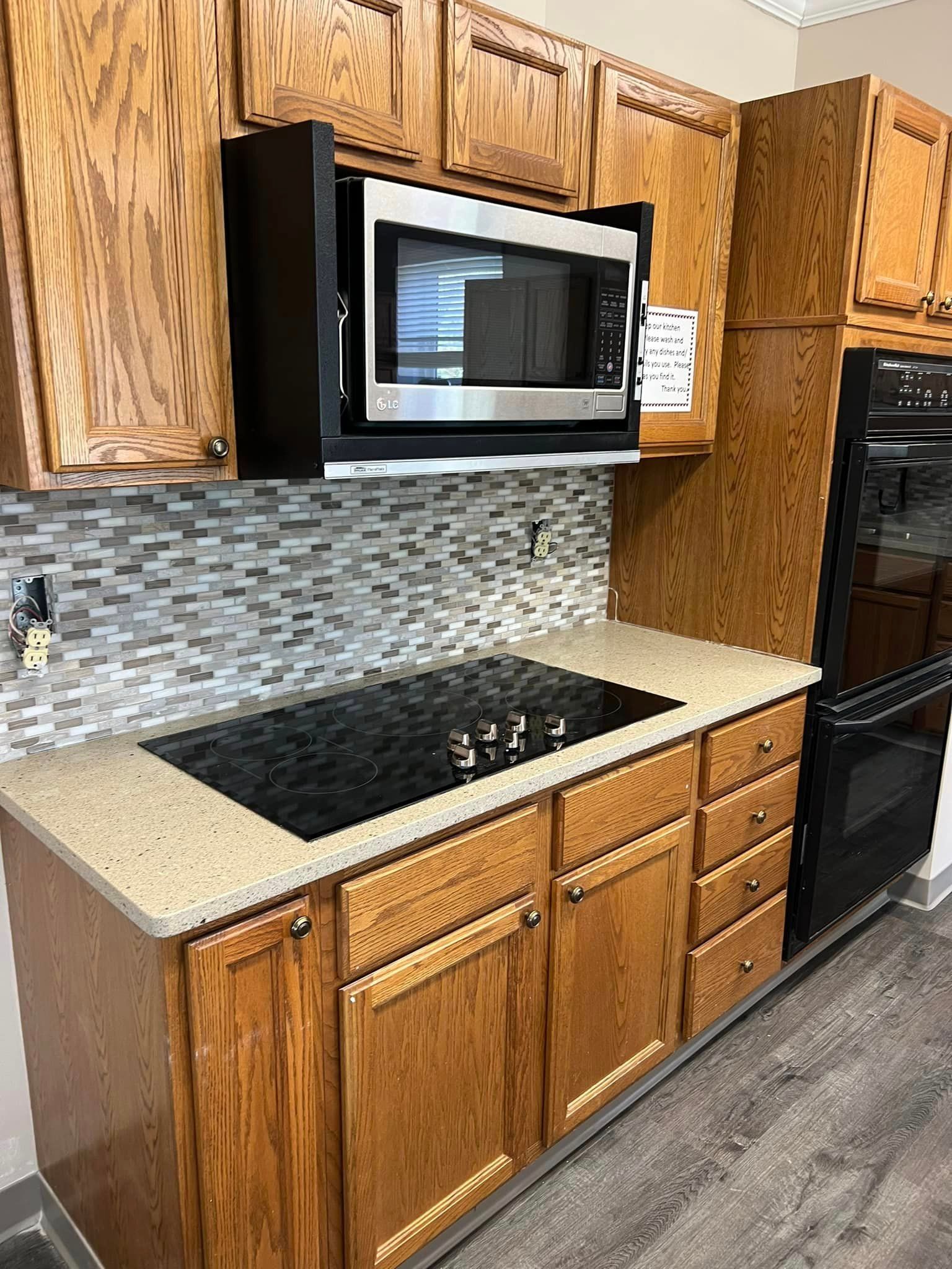A kitchen with wooden cabinets , a stove , a microwave , and an oven.
