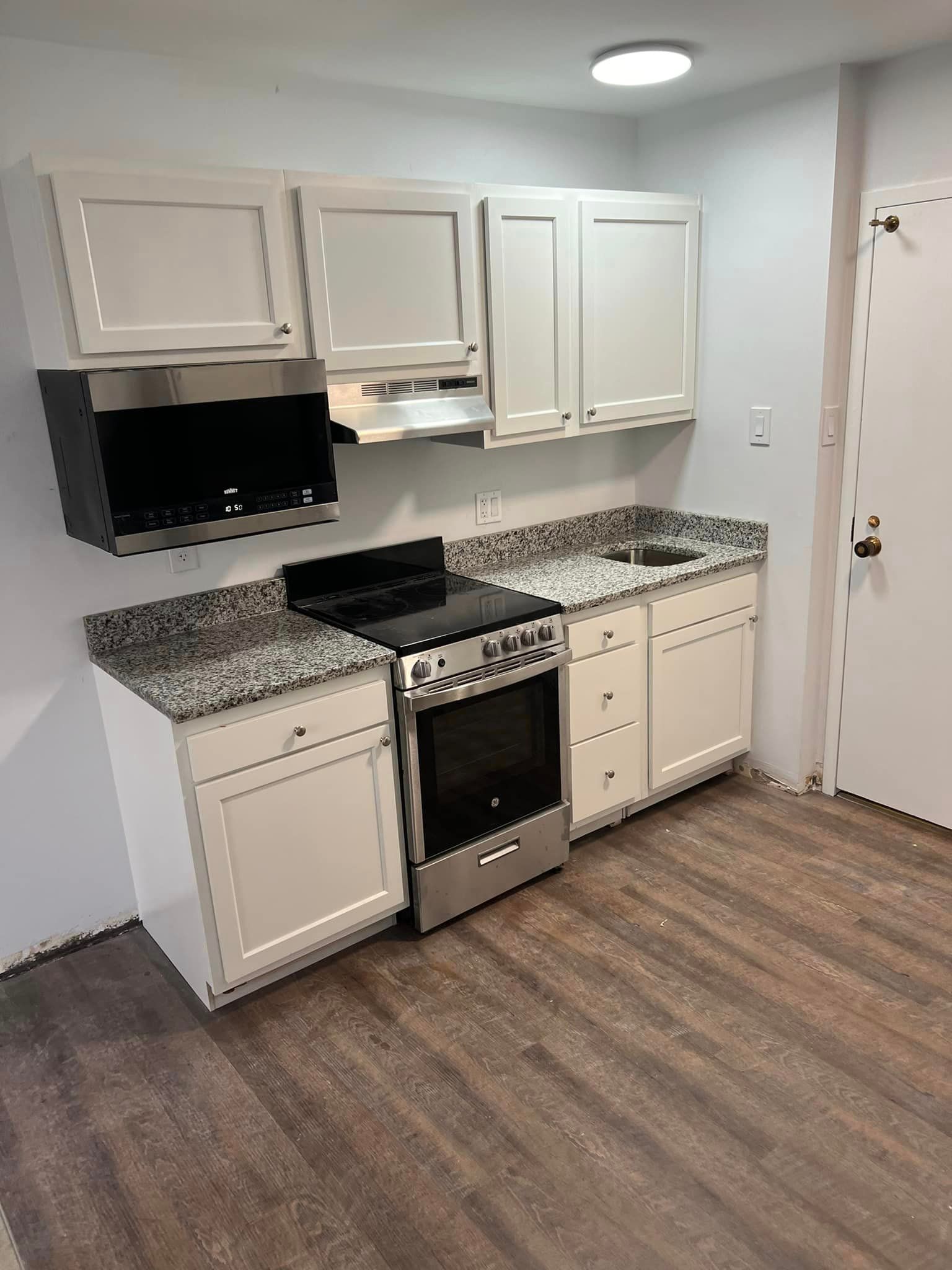A kitchen with white cabinets , a stove , and a sink.