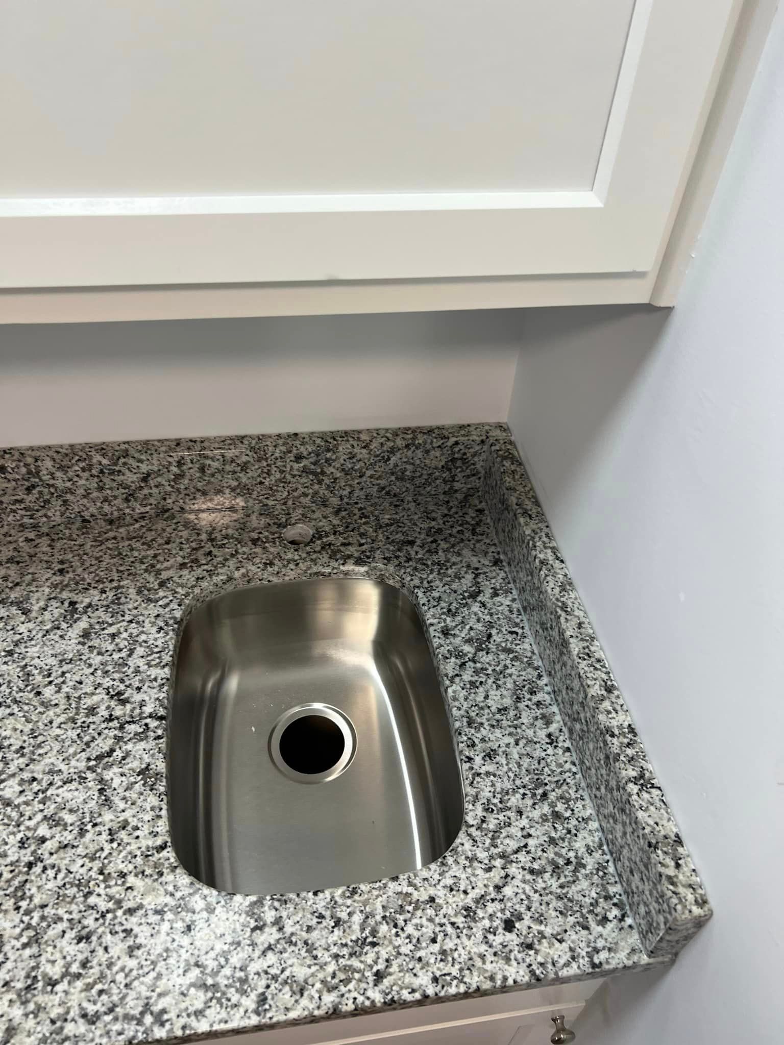 A stainless steel sink is sitting on top of a granite counter.