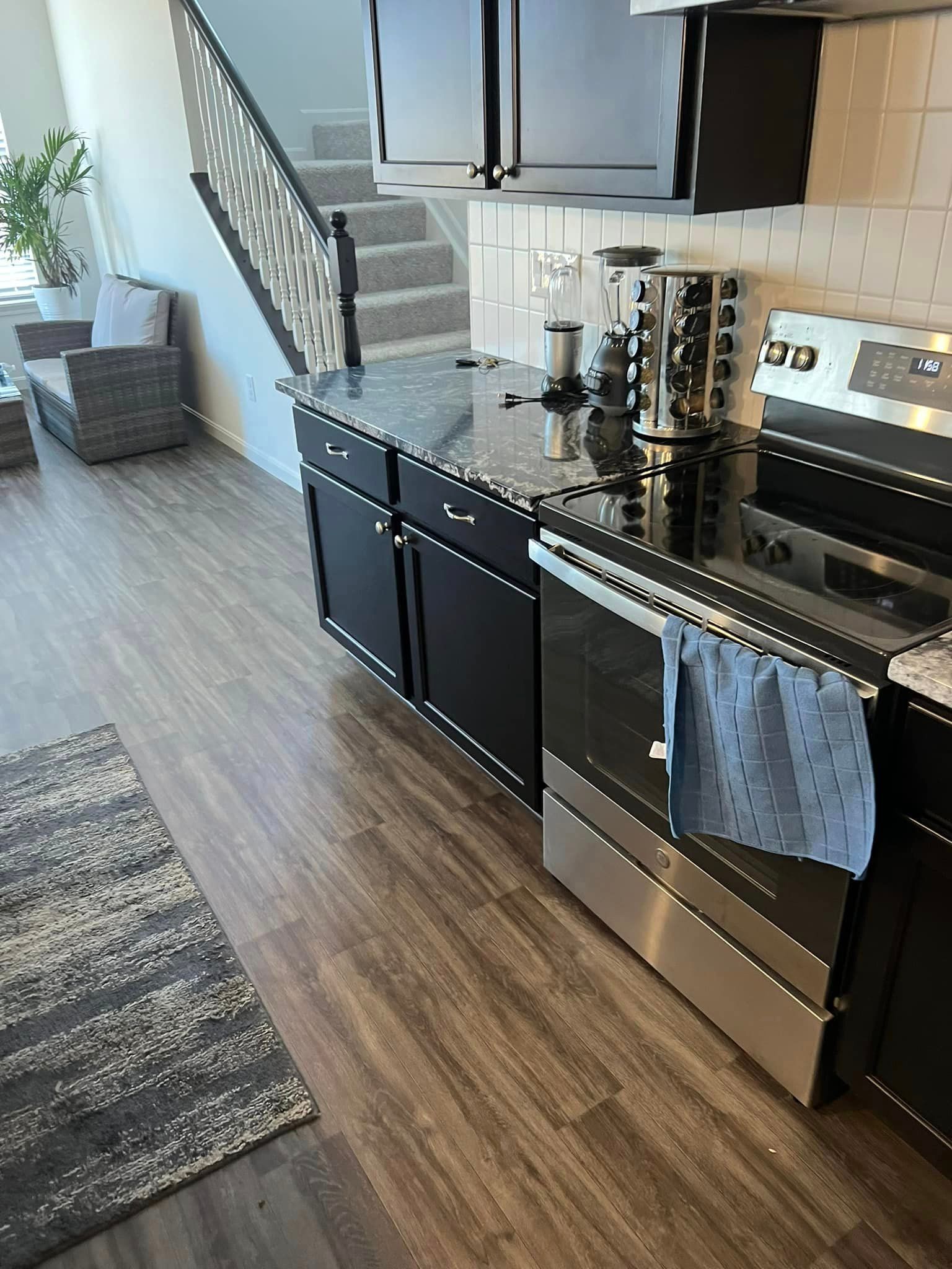 A kitchen with black cabinets , stainless steel appliances , a stove and a microwave.