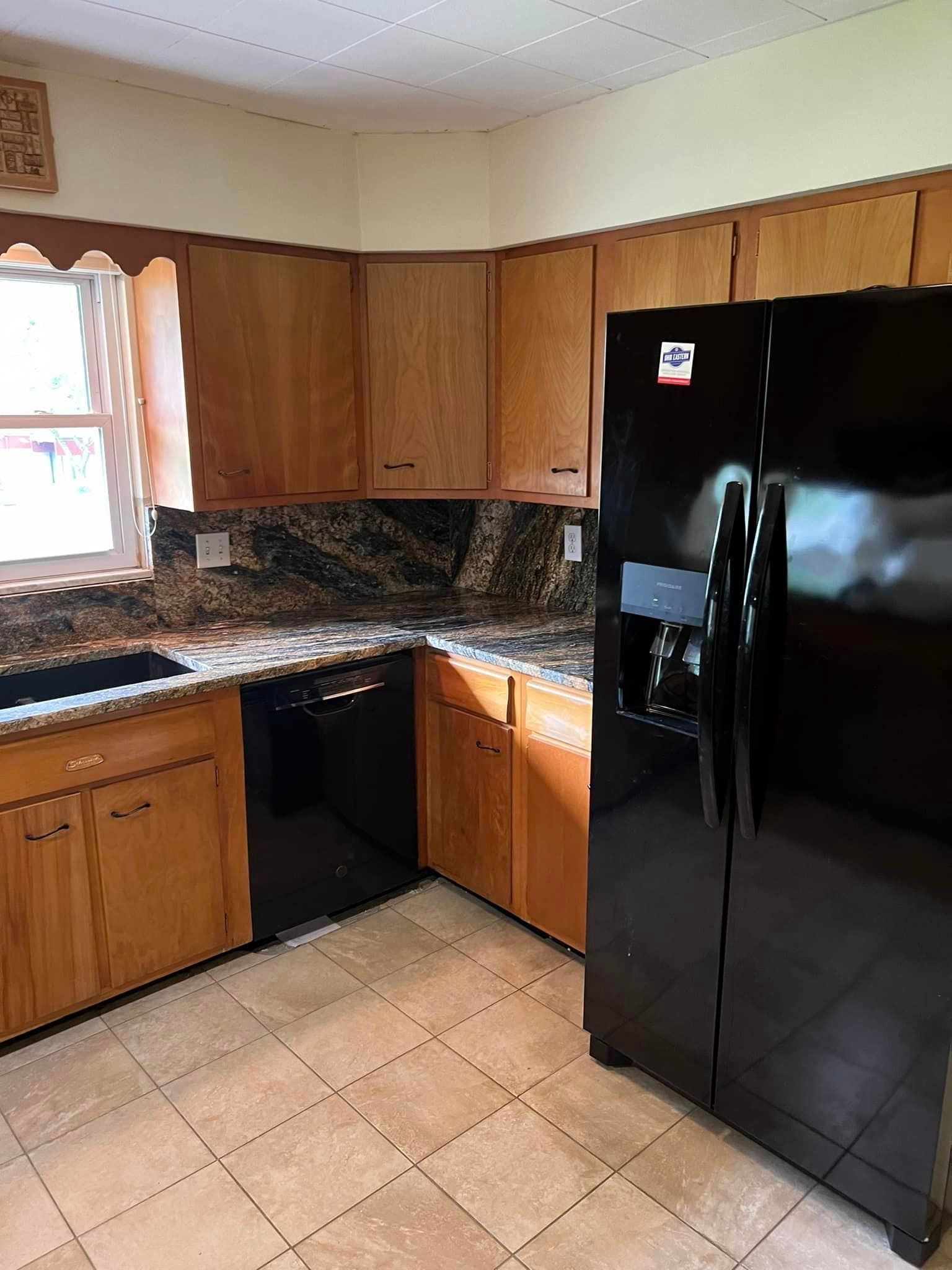 A kitchen with wooden cabinets and a black refrigerator.