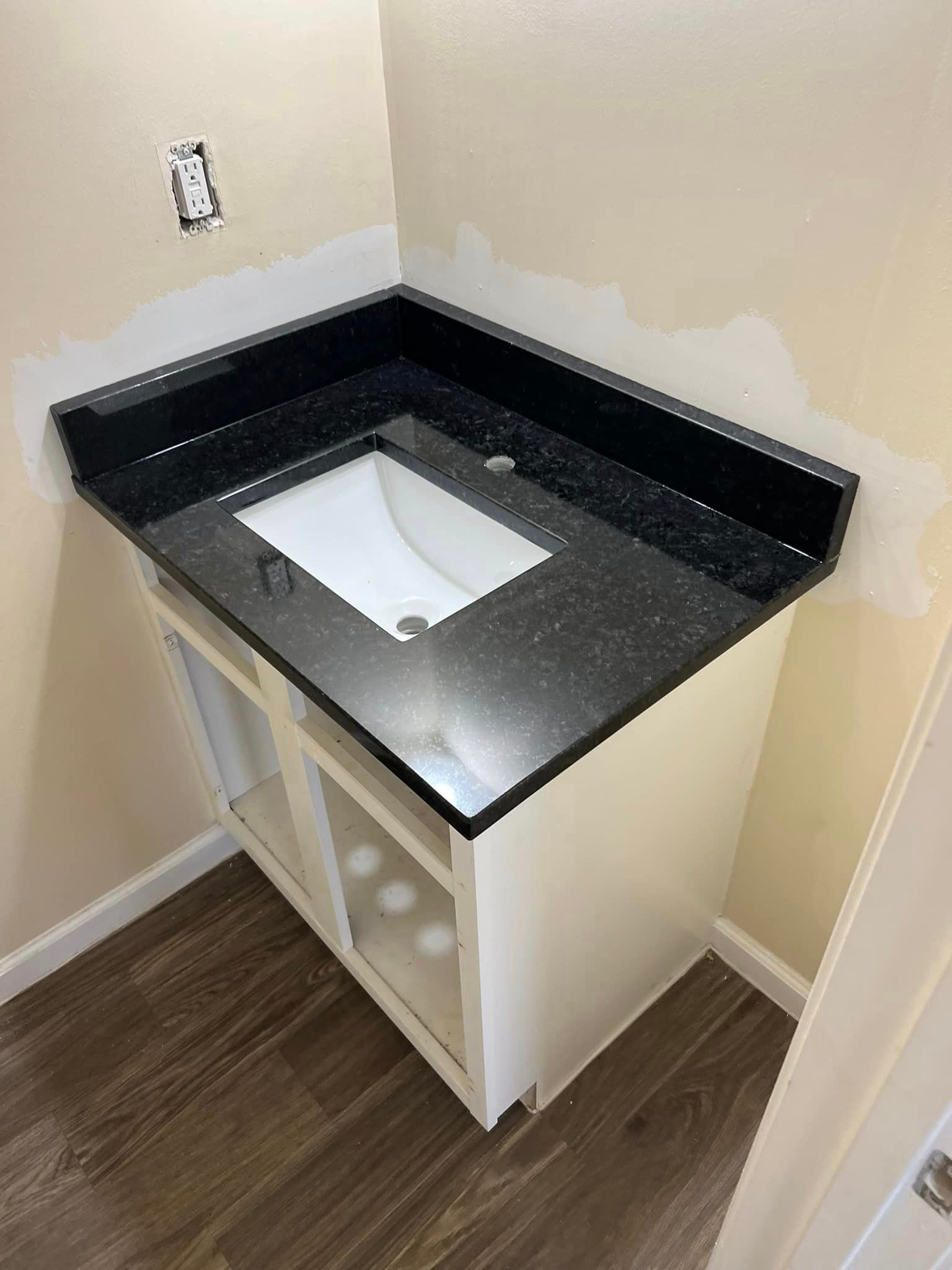 A bathroom vanity with a black granite counter top and a white sink.