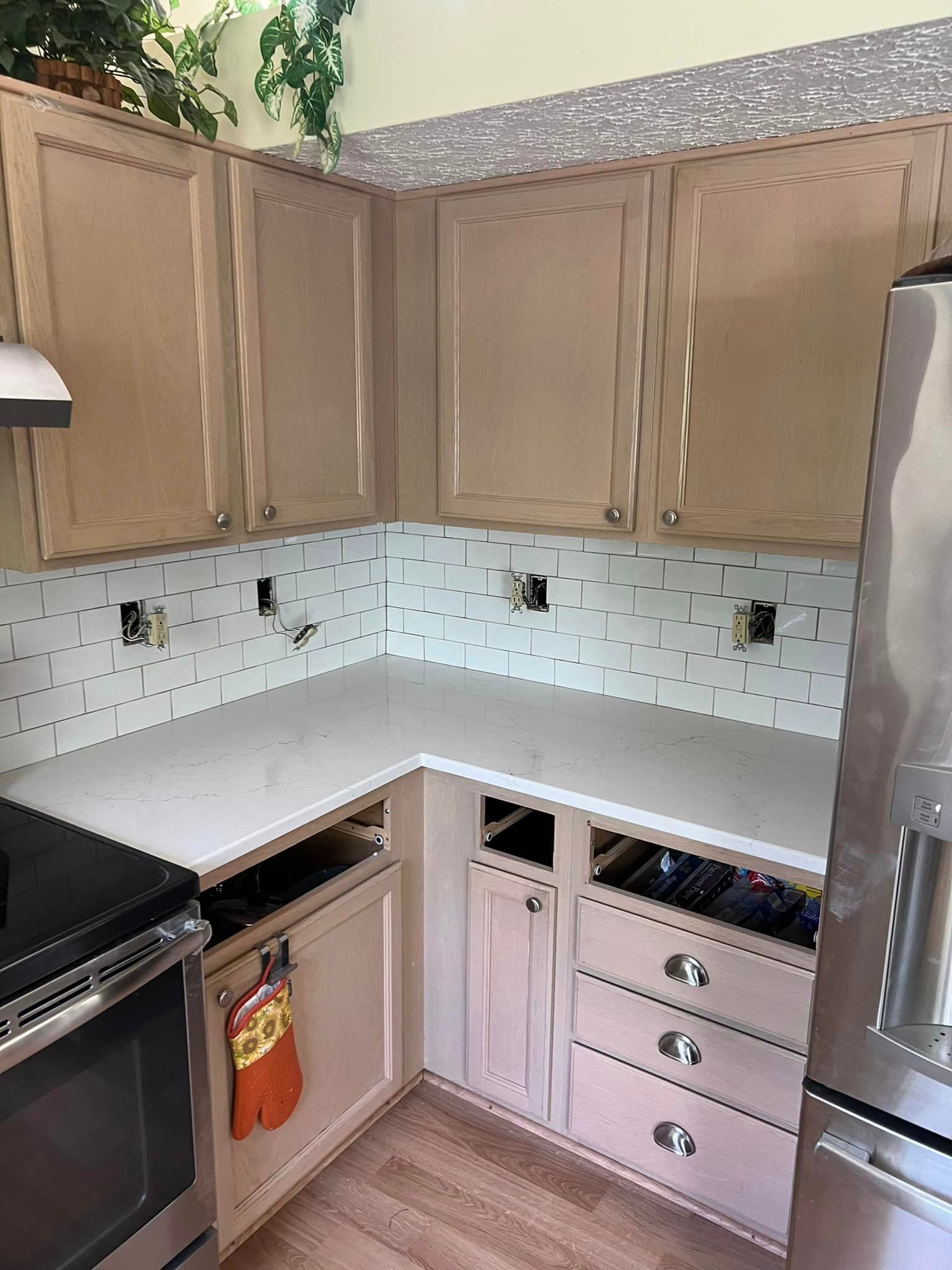 A kitchen with a stainless steel refrigerator , stove , cabinets and counter tops.