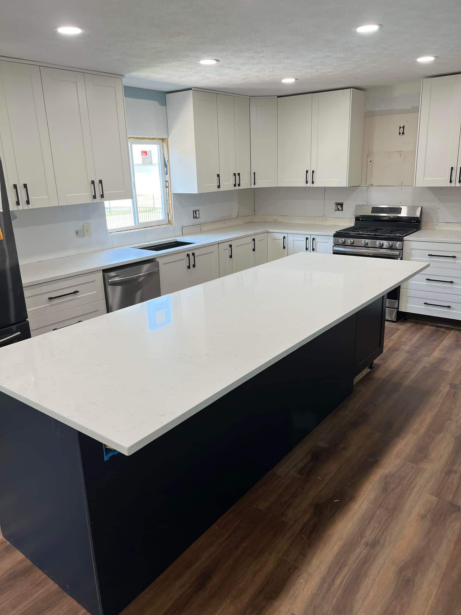 A kitchen with a large island and white counter tops