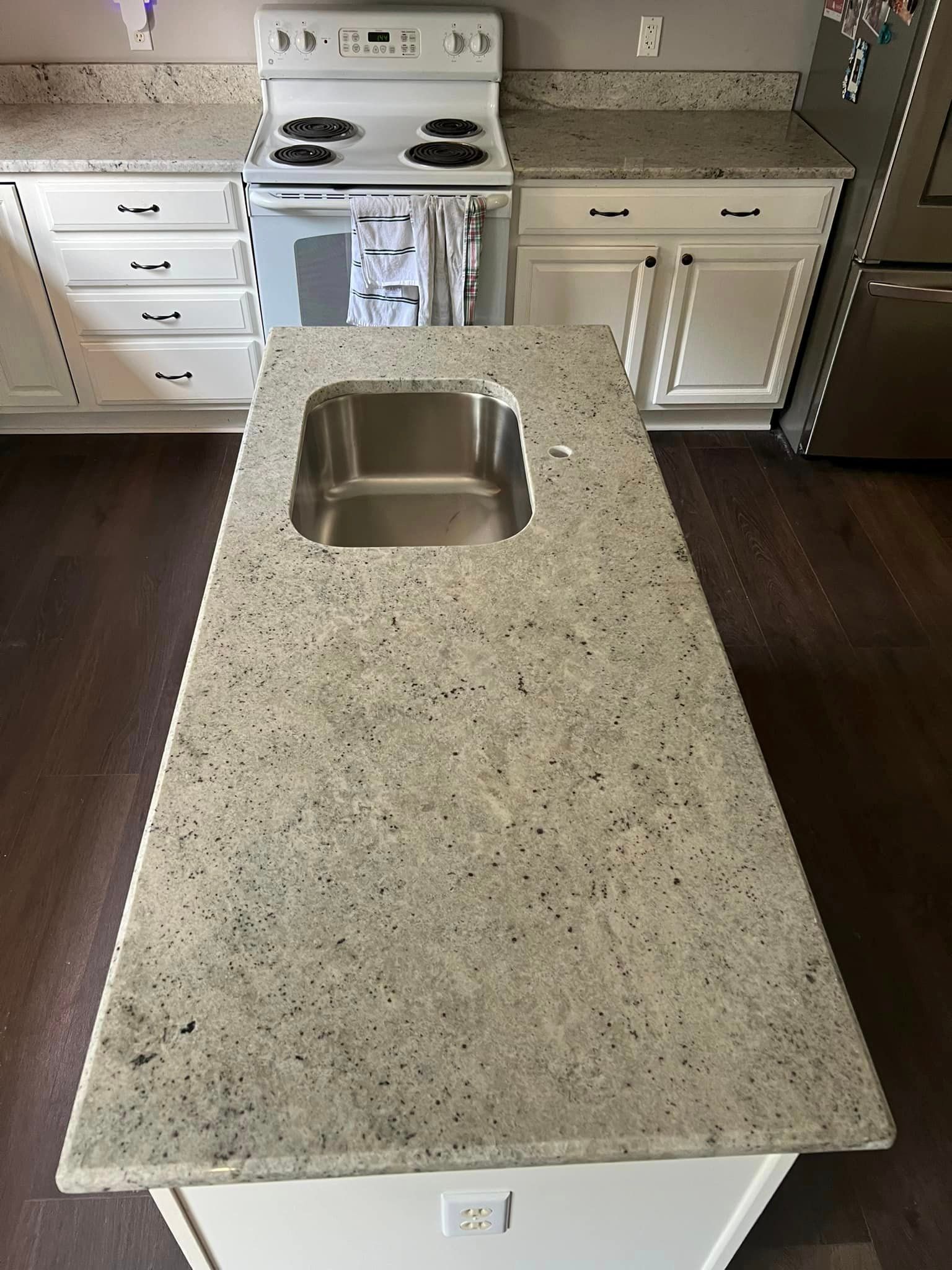 A kitchen with a large granite counter top and a stainless steel sink.