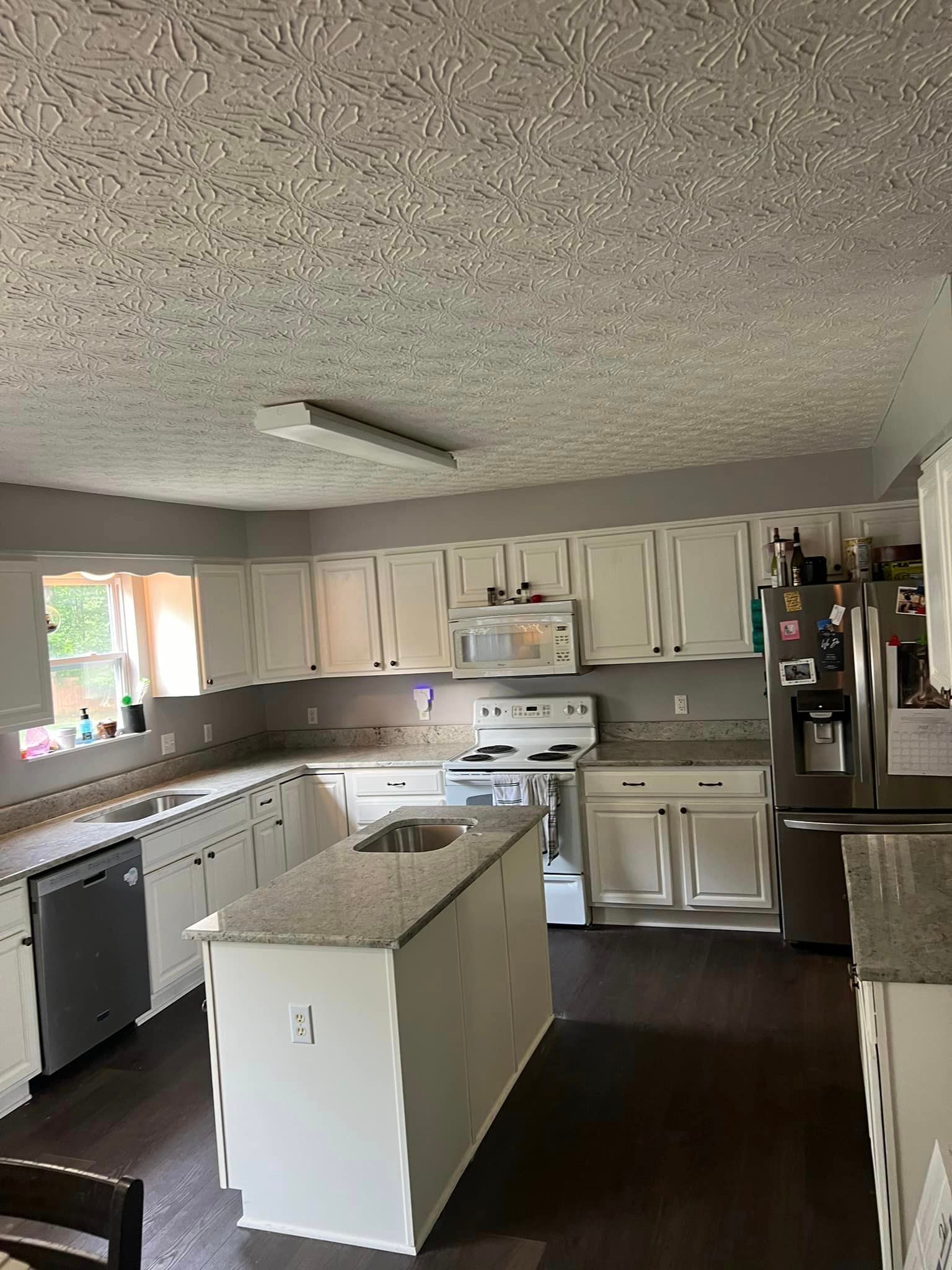 A kitchen with white cabinets , granite counter tops , stainless steel appliances and a large island.