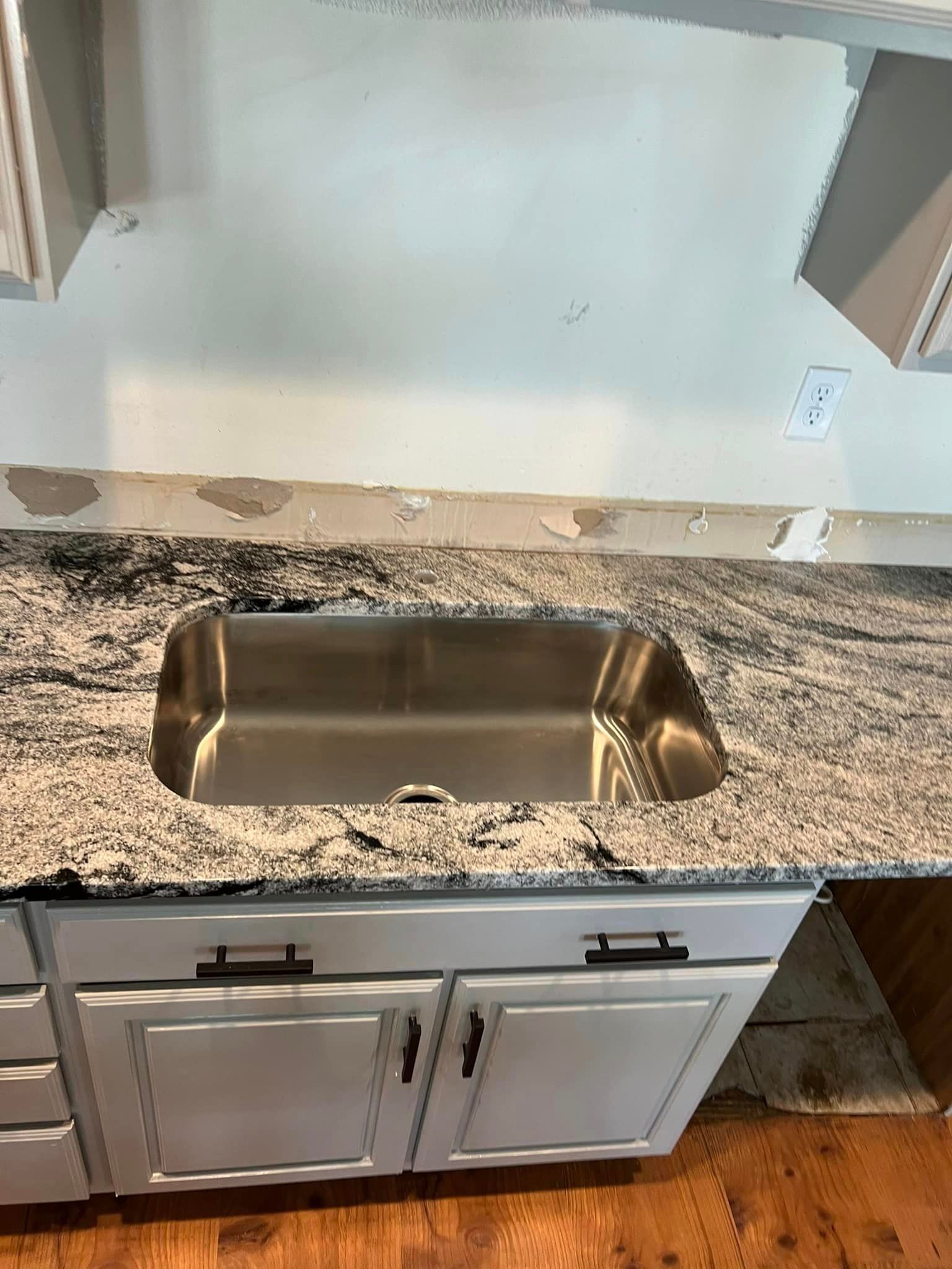 A kitchen sink is sitting on top of a granite counter top.