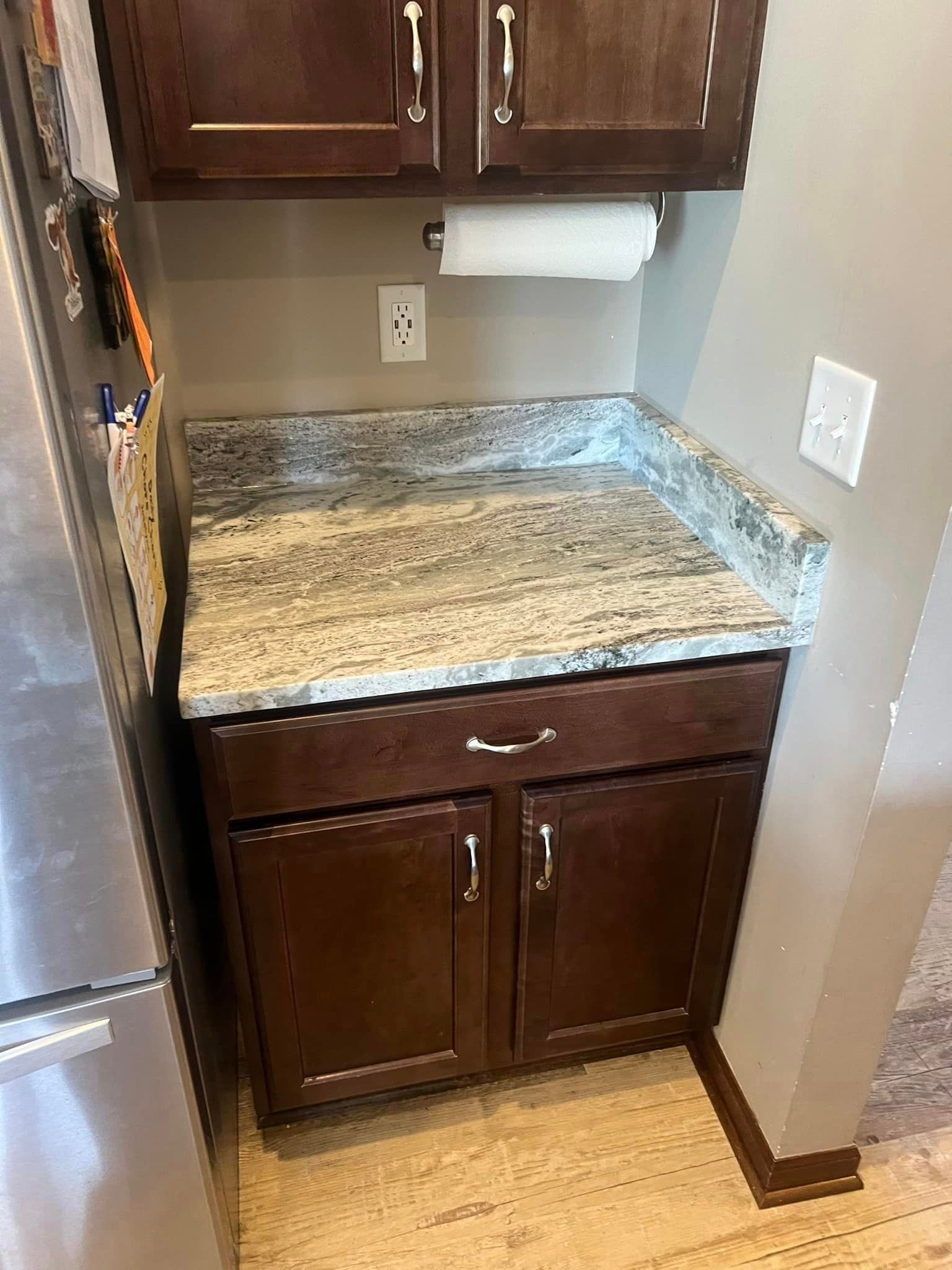 A kitchen with a granite counter top and stainless steel refrigerator.