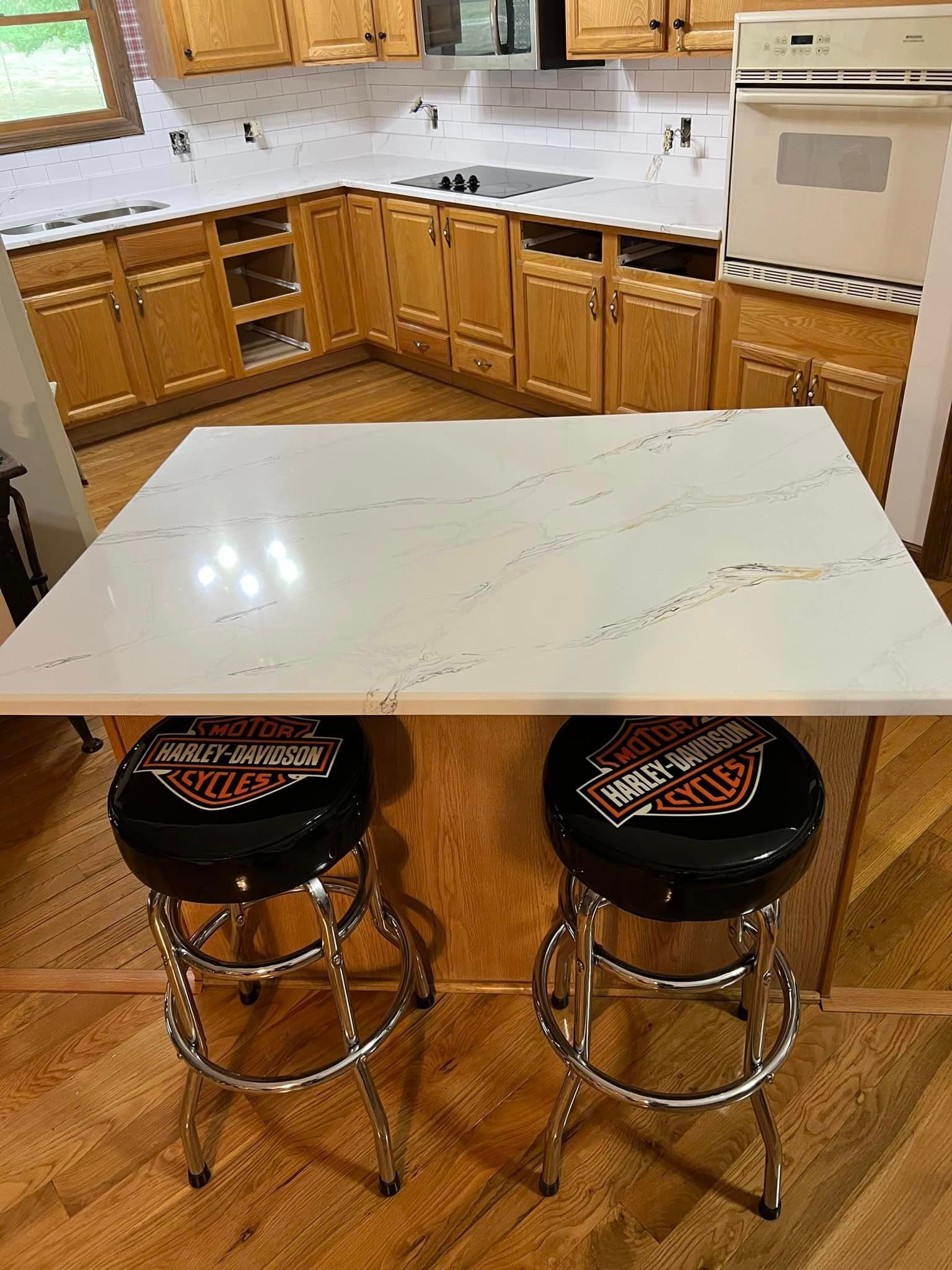 A kitchen with two bar stools and a table.