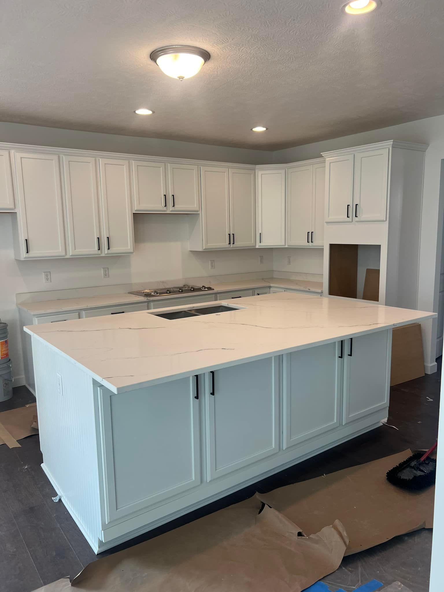 A kitchen with white cabinets and a large island in the middle.