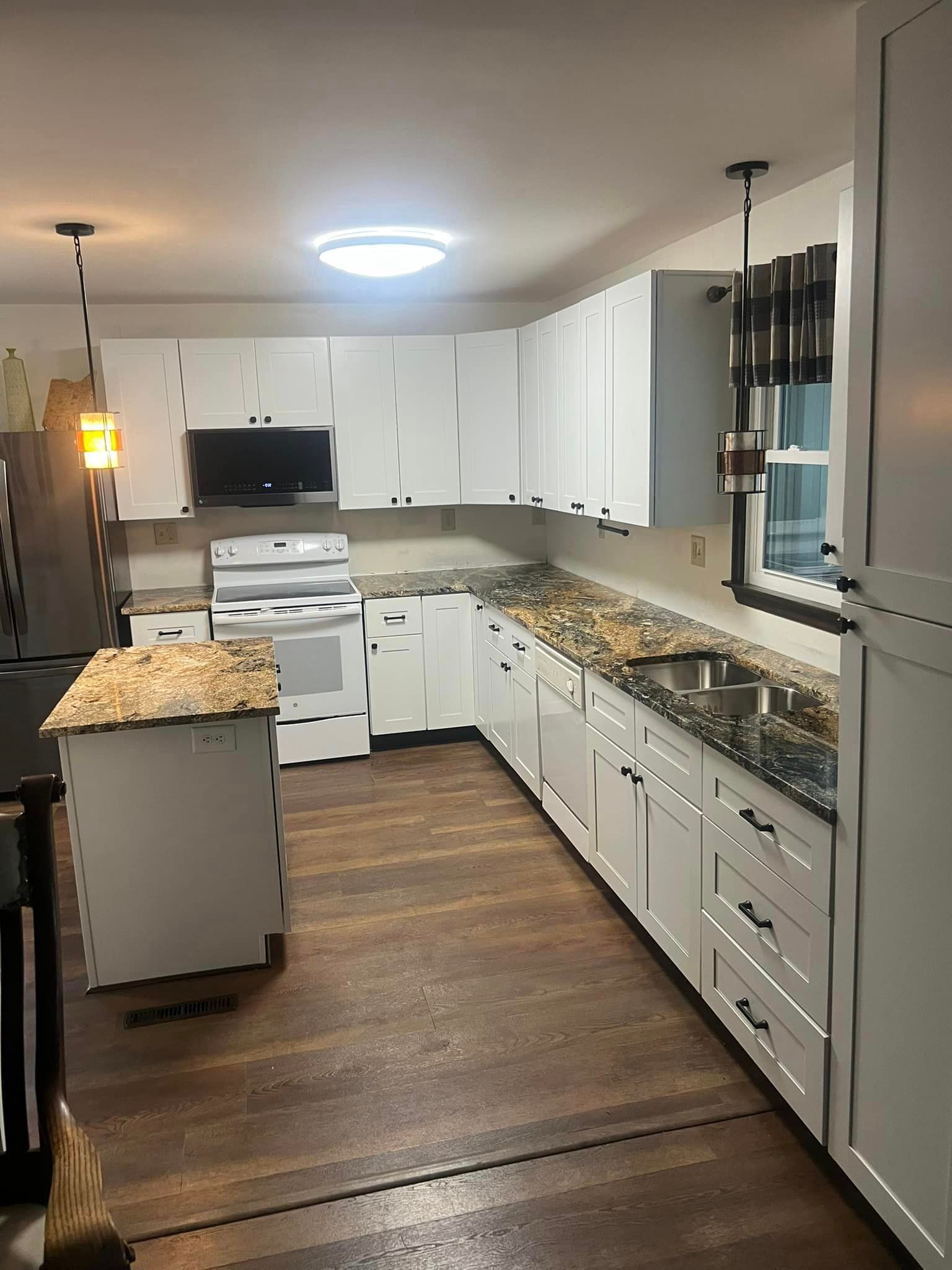 A kitchen with white cabinets and granite counter tops.