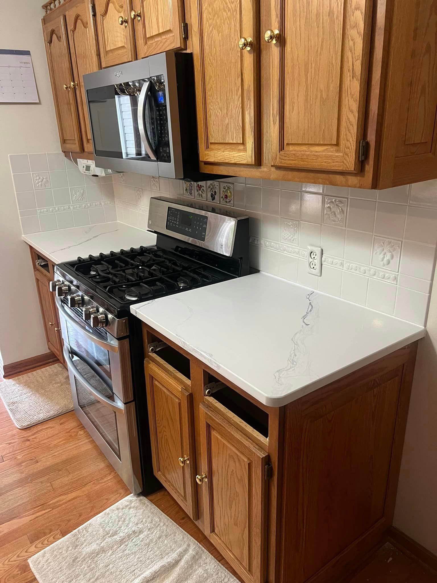 A kitchen with wooden cabinets , stainless steel appliances , a stove and a microwave.