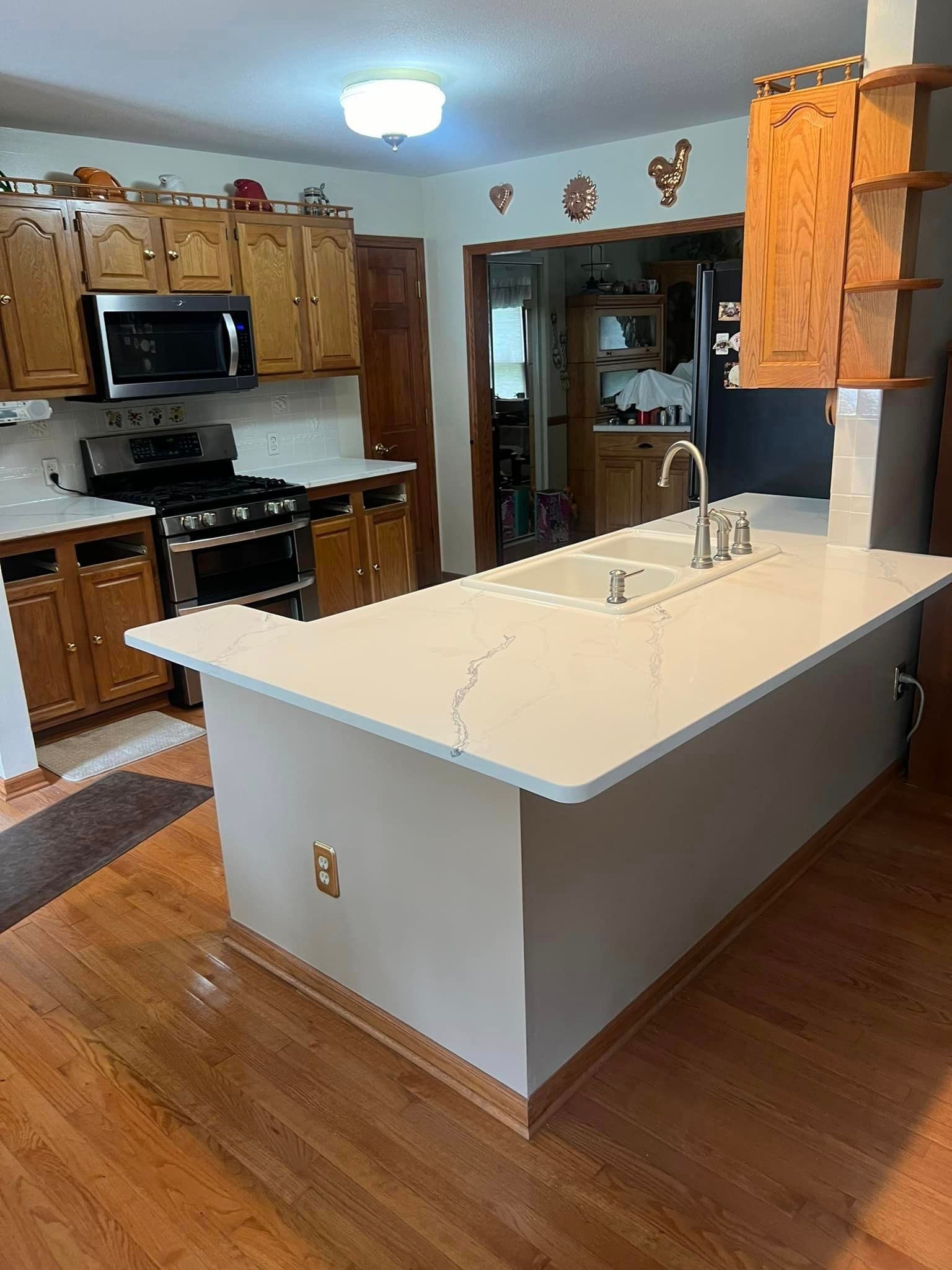 A kitchen with a large island , sink , stove and microwave.
