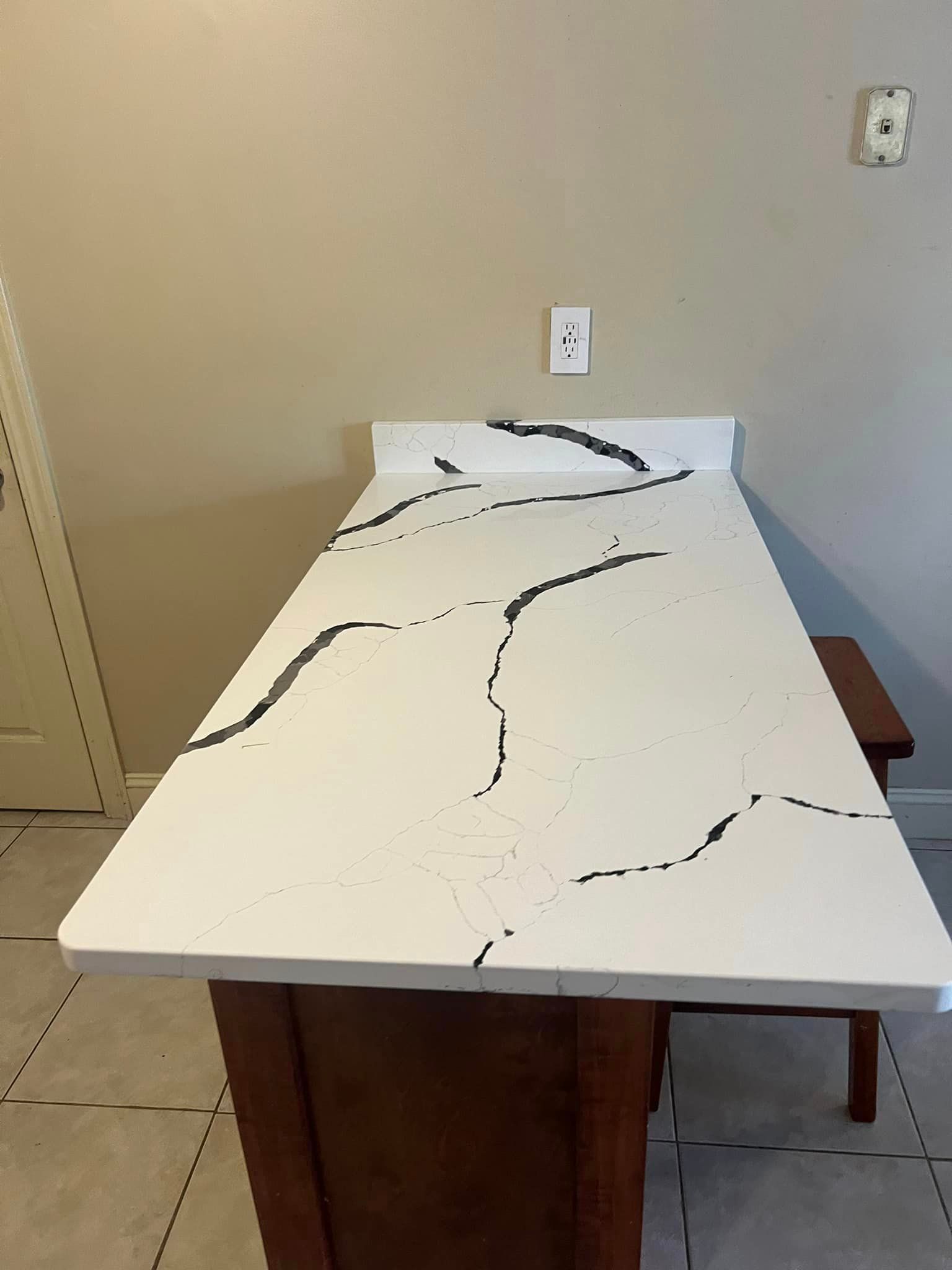 A kitchen island with a white counter top and black lines on it.