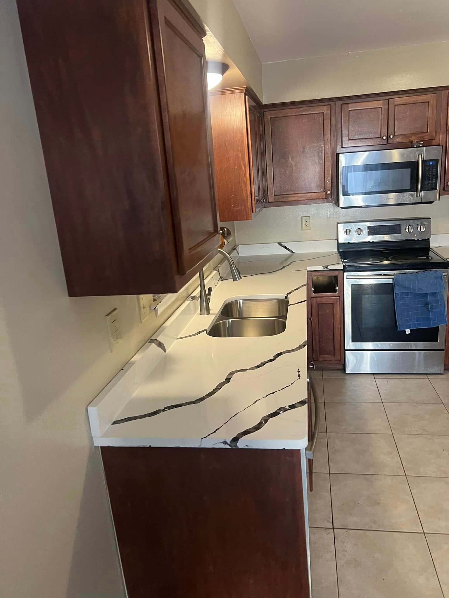 A kitchen with a sink , stove , microwave and cabinets.
