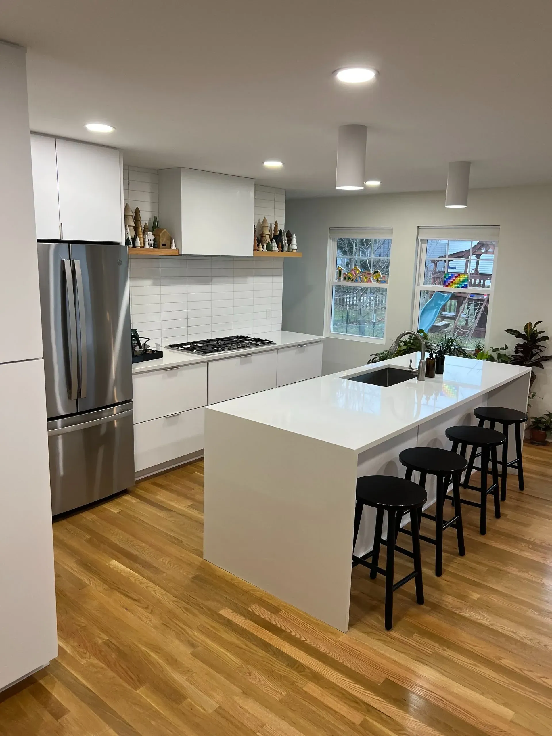 A kitchen with a large island , stools and a refrigerator.