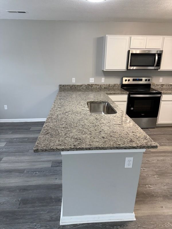 A kitchen with a black counter top and white cabinets is being remodeled.