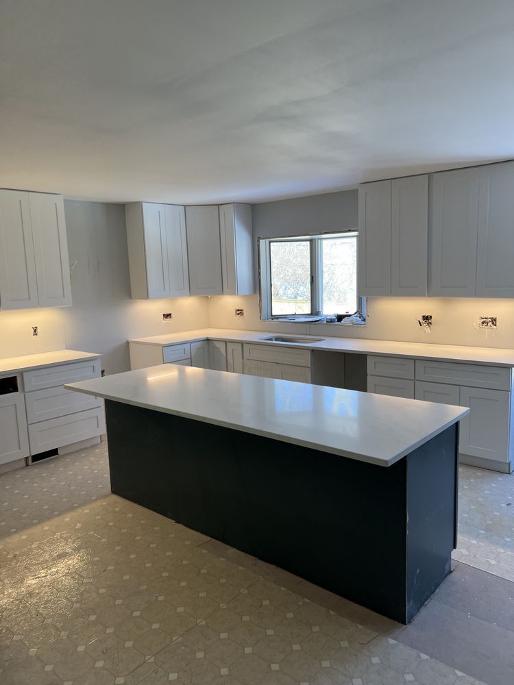 A kitchen with white cabinets and a large island in the middle