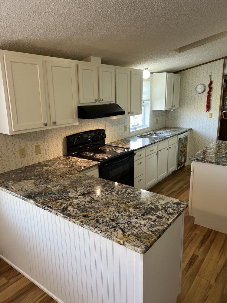 A kitchen with granite counter tops , white cabinets and a stove.