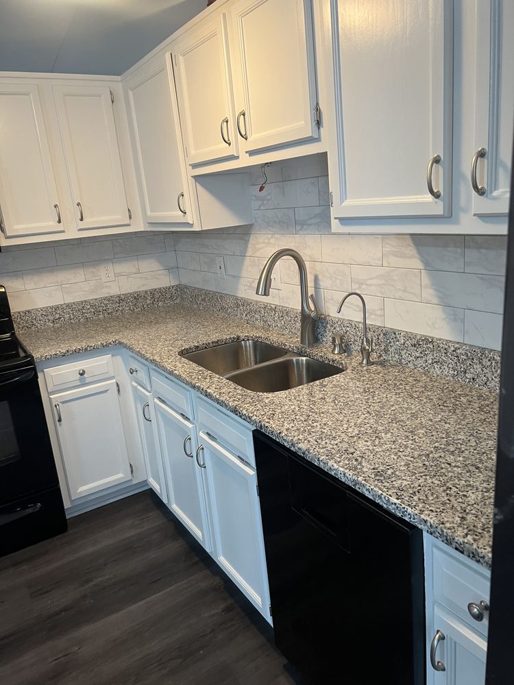 A kitchen with white cabinets , granite counter tops , a sink and a stove.