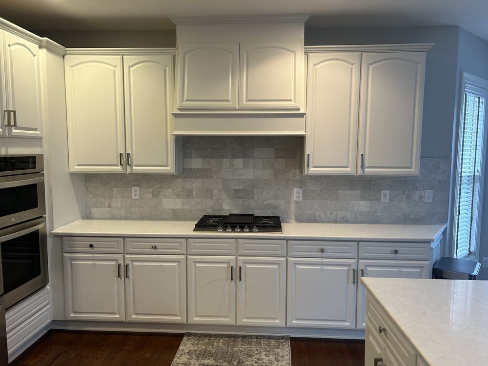 A kitchen with white cabinets and a stove top oven.