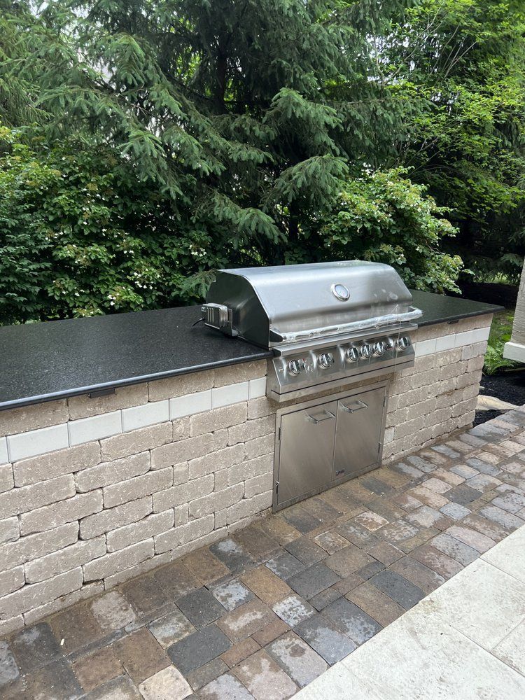 A grill is sitting on top of a brick wall.