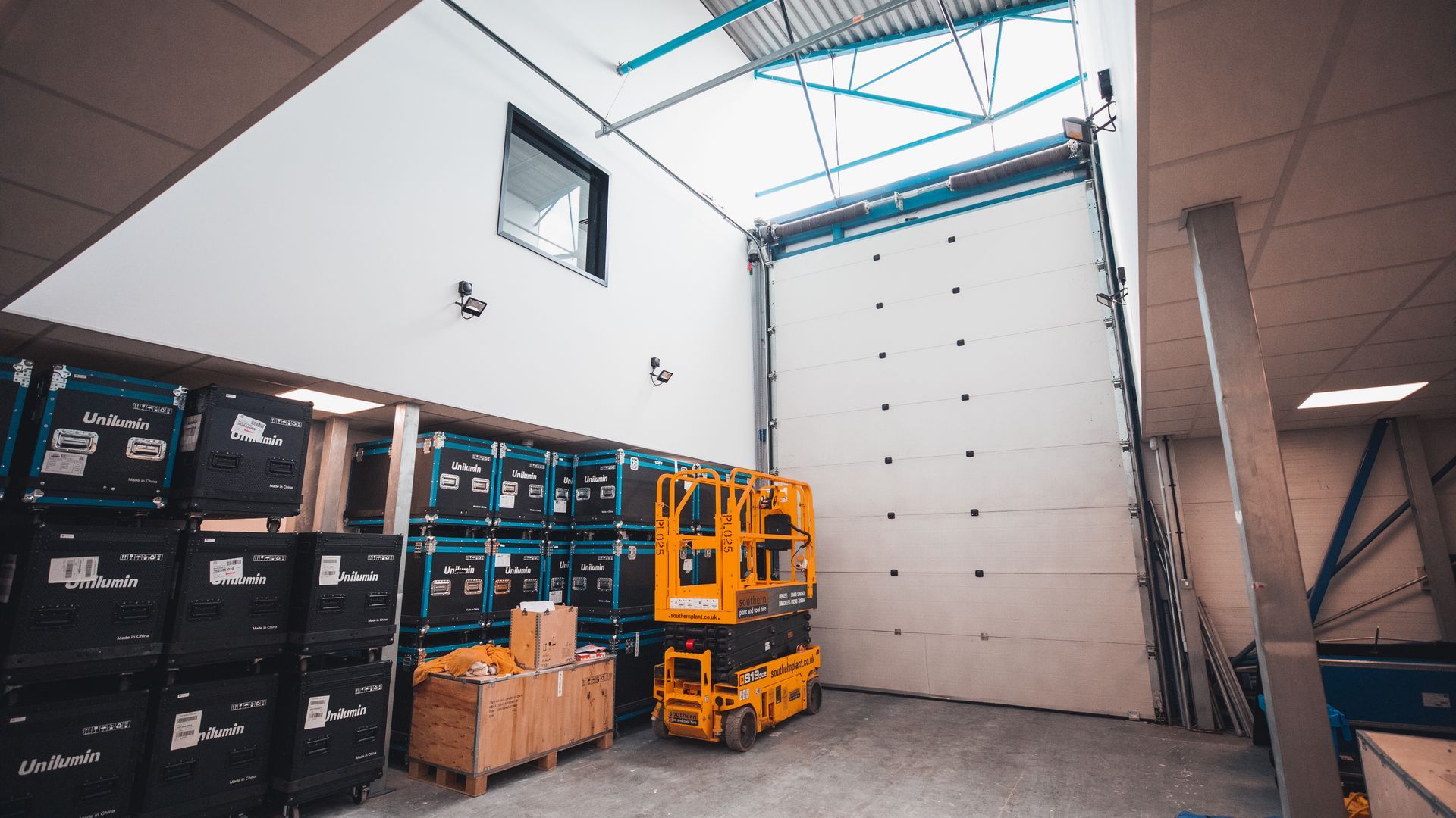 A large warehouse with a lot of boxes and a yellow lift.