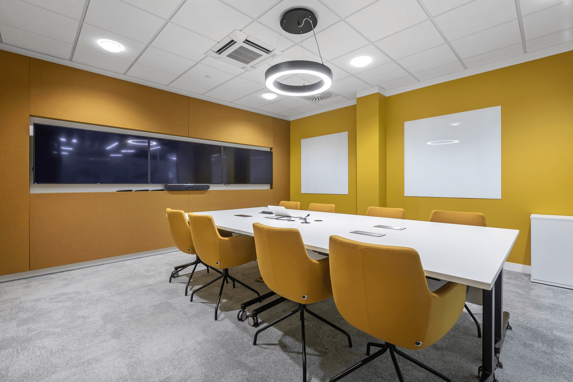 A conference room with a long table and yellow chairs.