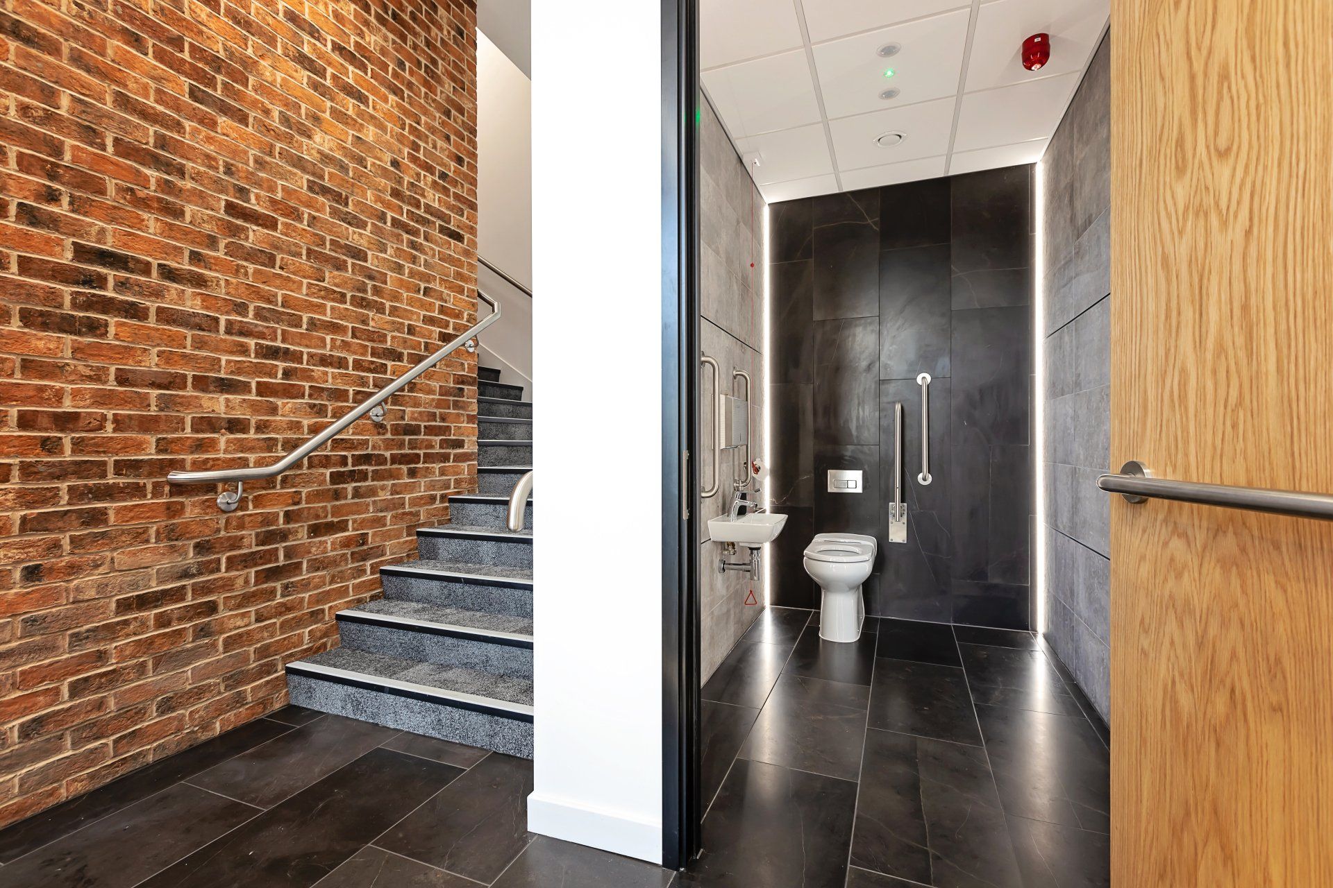 A bathroom with a toilet , sink and stairs.