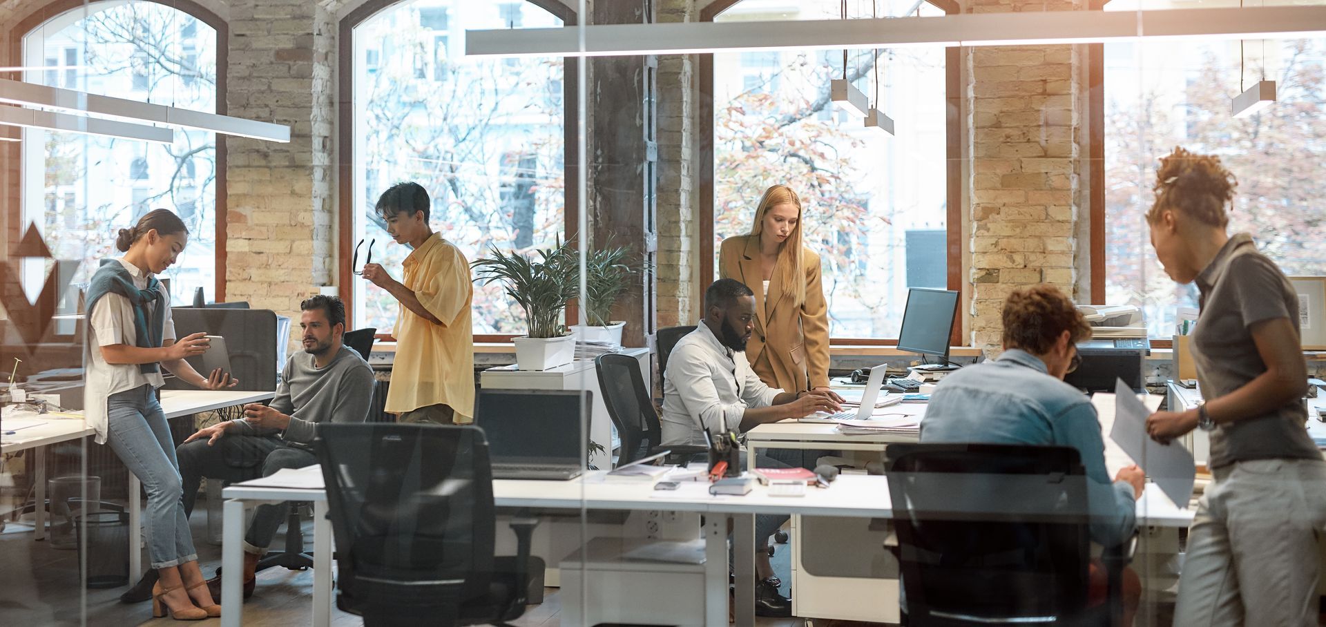 A group of people are sitting at desks in an office.