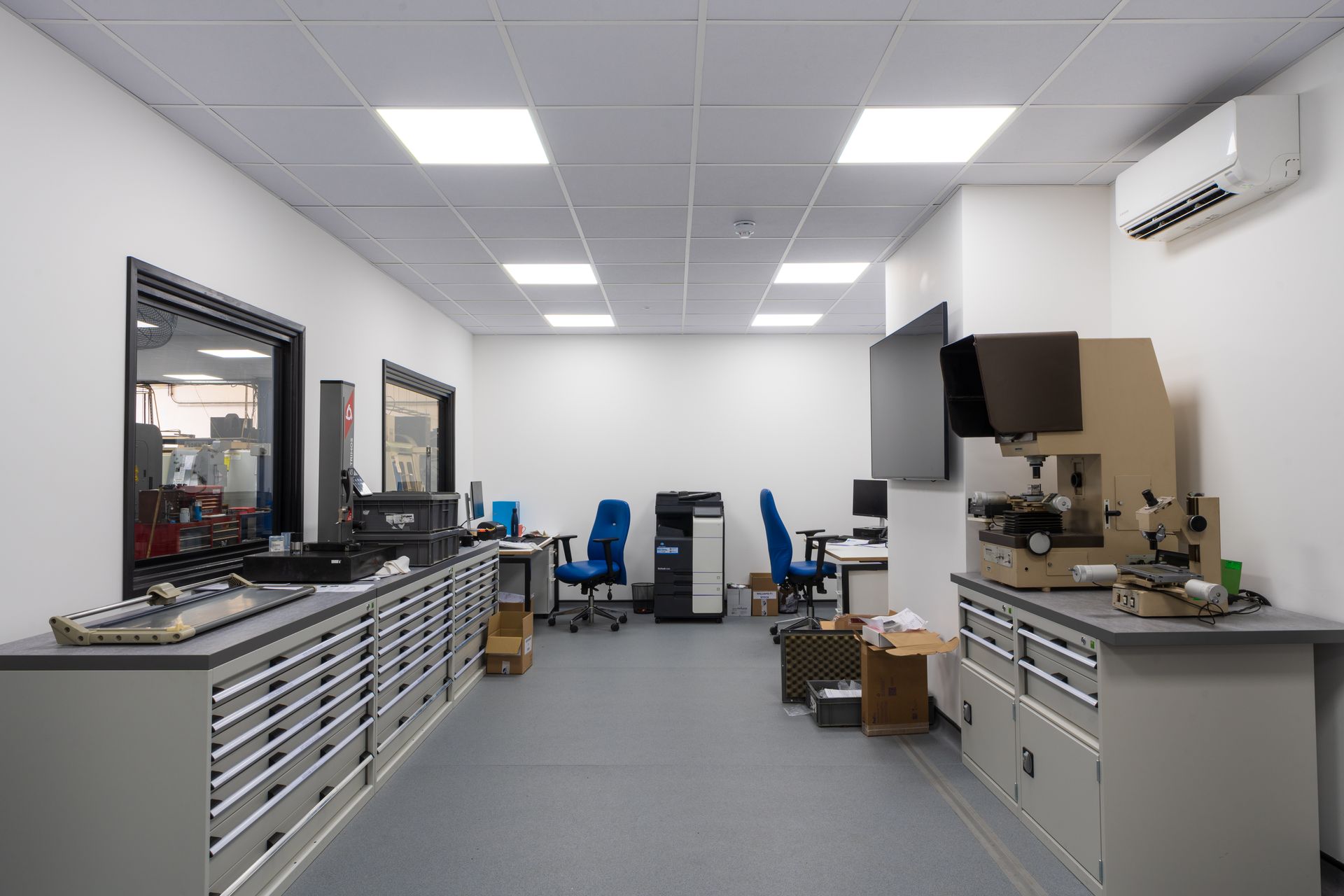 A conference room with a long wooden table and chairs and a flat screen tv on the wall.