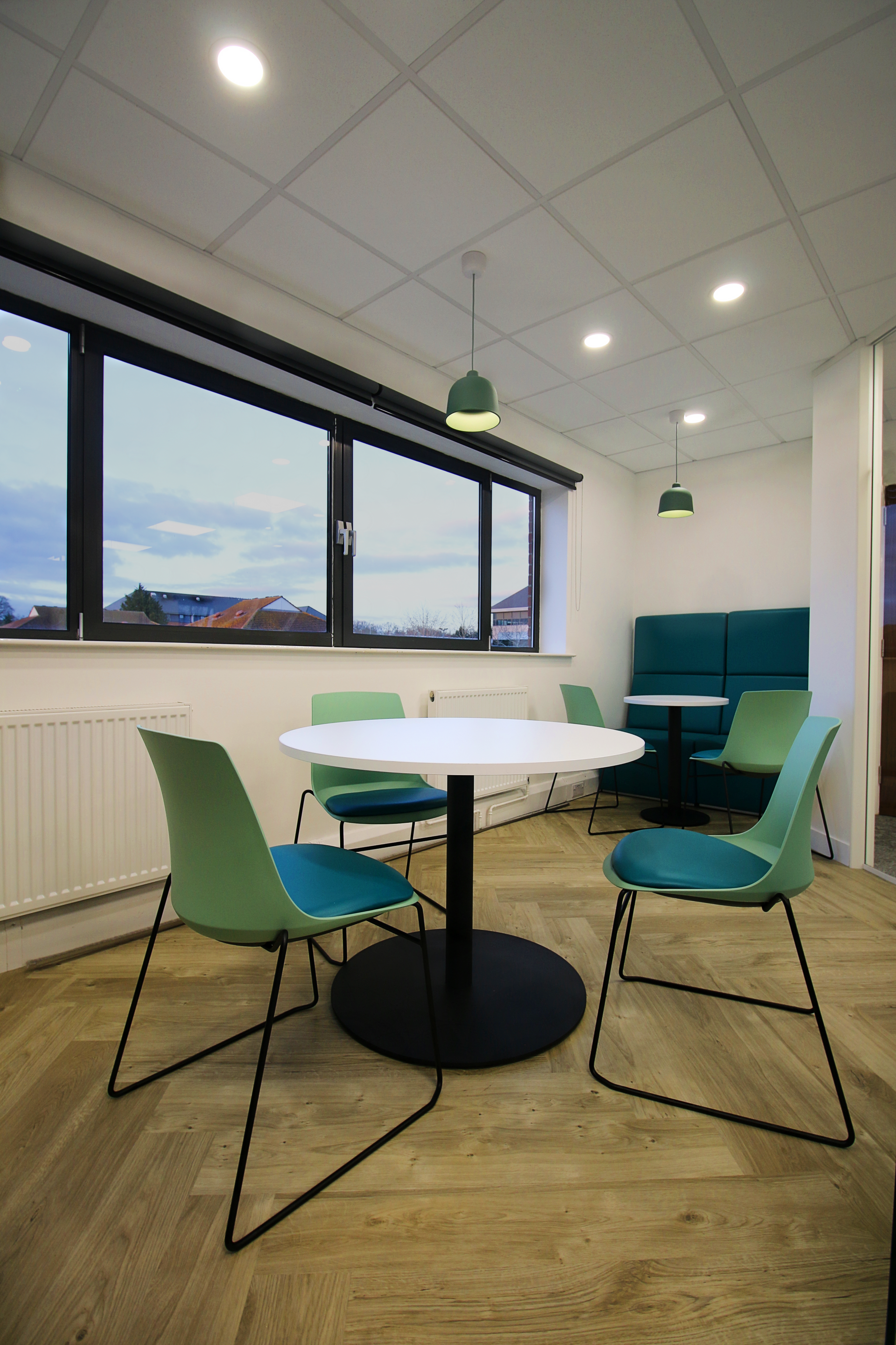A room with a table and chairs in front of a window.