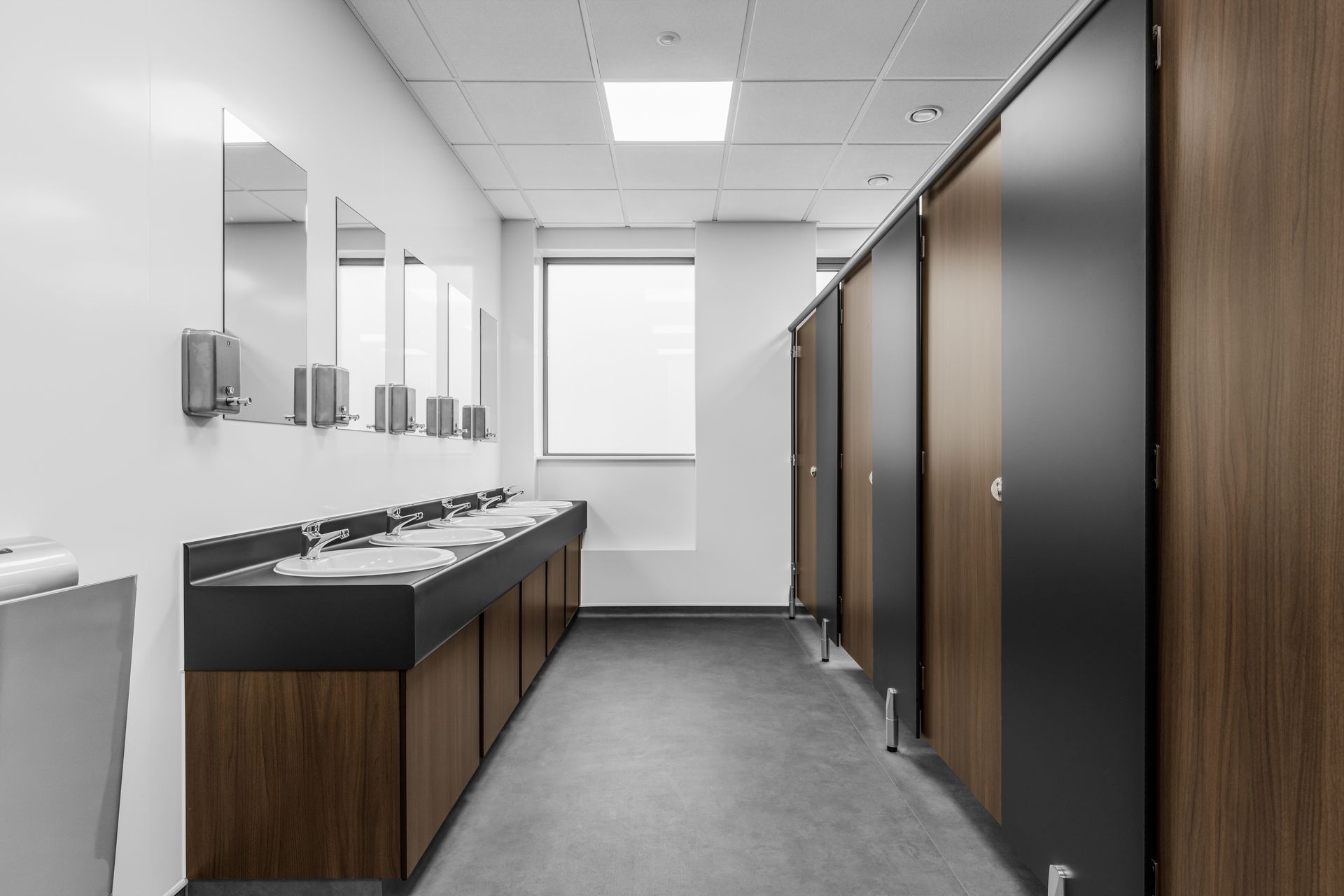 A long hallway in a public restroom with wooden cabinets and sinks.